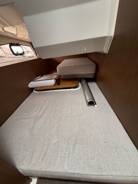 Interior of a 2021 Jeanneau NC 1095 with cushioned bed and wood paneling.