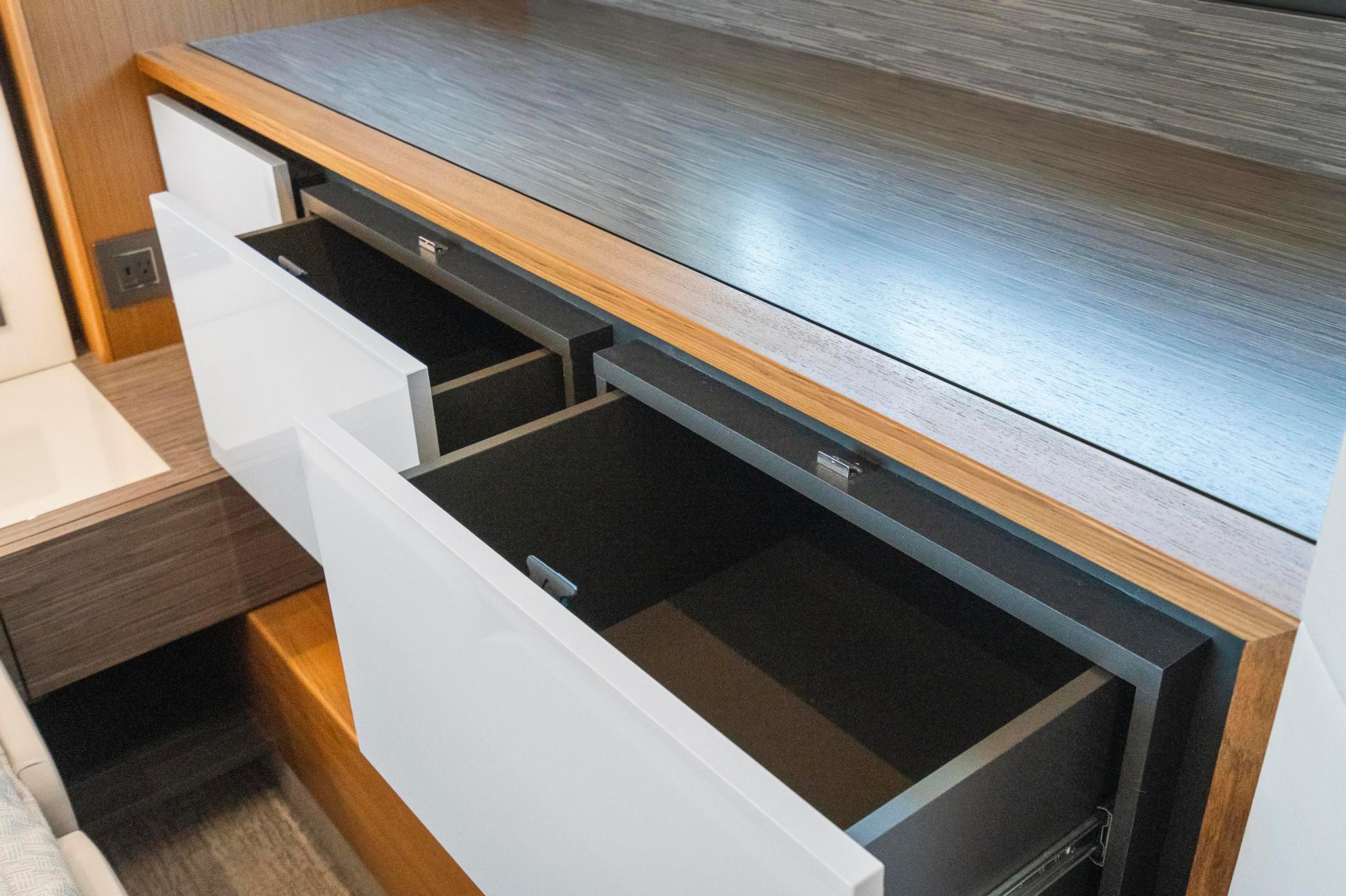Open drawers in the 2022 Tiara Yachts C49 Coupe interior, showcasing sleek wooden design.