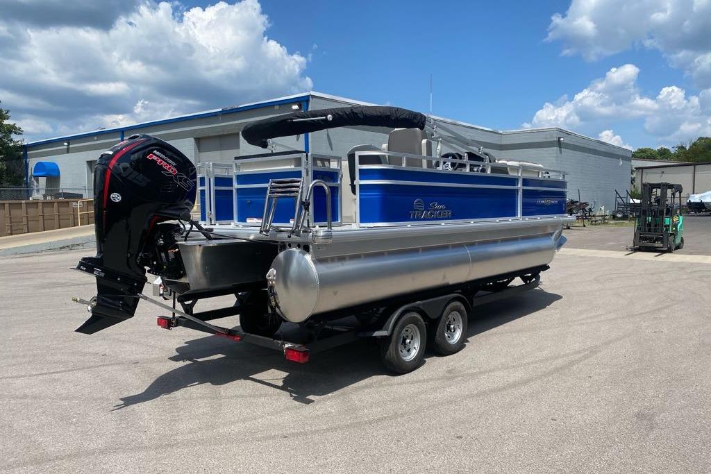2026 Sun Tracker Fishin' Barge 20 DLX pontoon boat on trailer, parked outdoors.