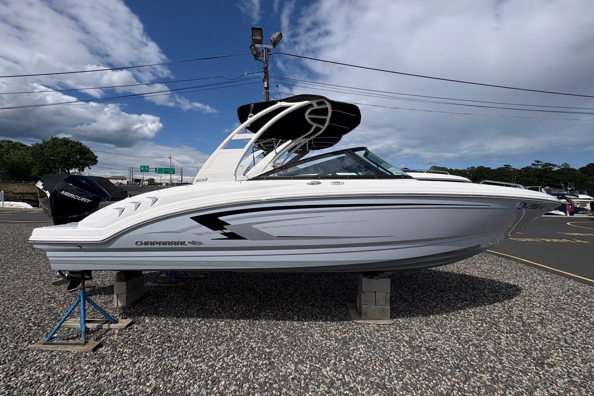 2026 Chaparral 23 SSi OB boat displayed outdoors on a gravel surface.