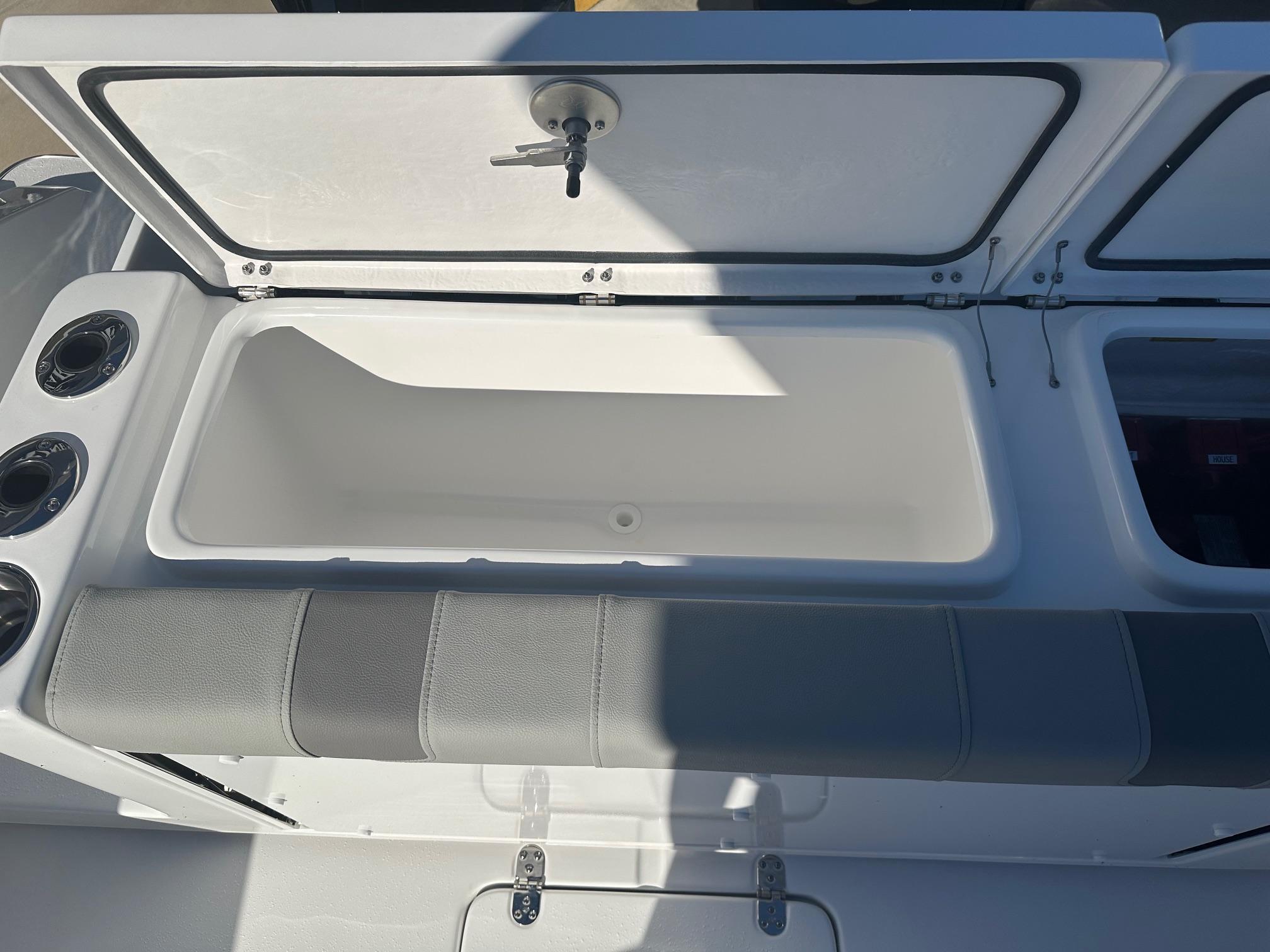 Open storage compartment on 2025 Cape Horn 28XS boat, featuring cushioned seating and cup holders.
