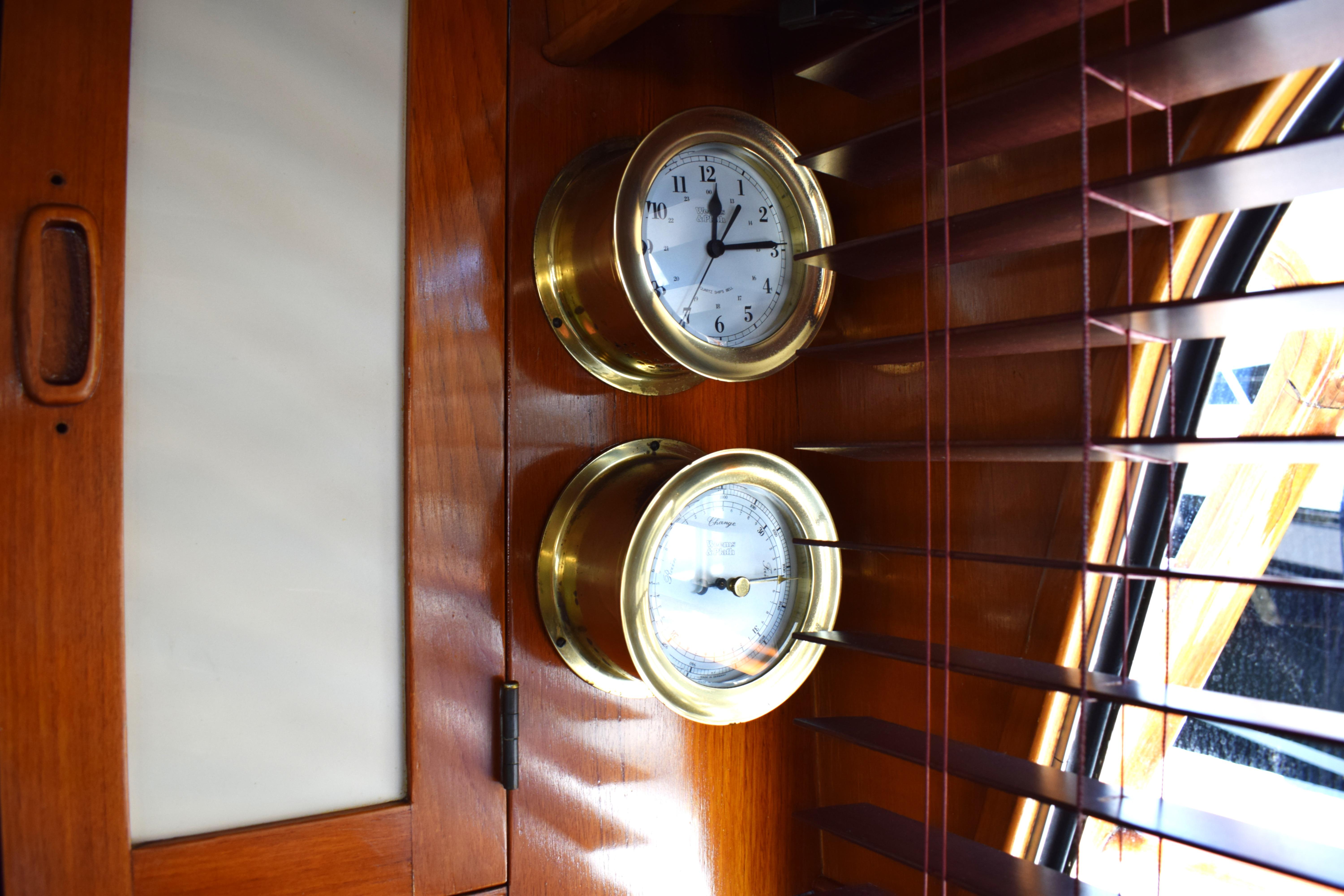 Brass clock and barometer on 1980 Cheoy Lee 52 Motorsailer interior wood paneling.