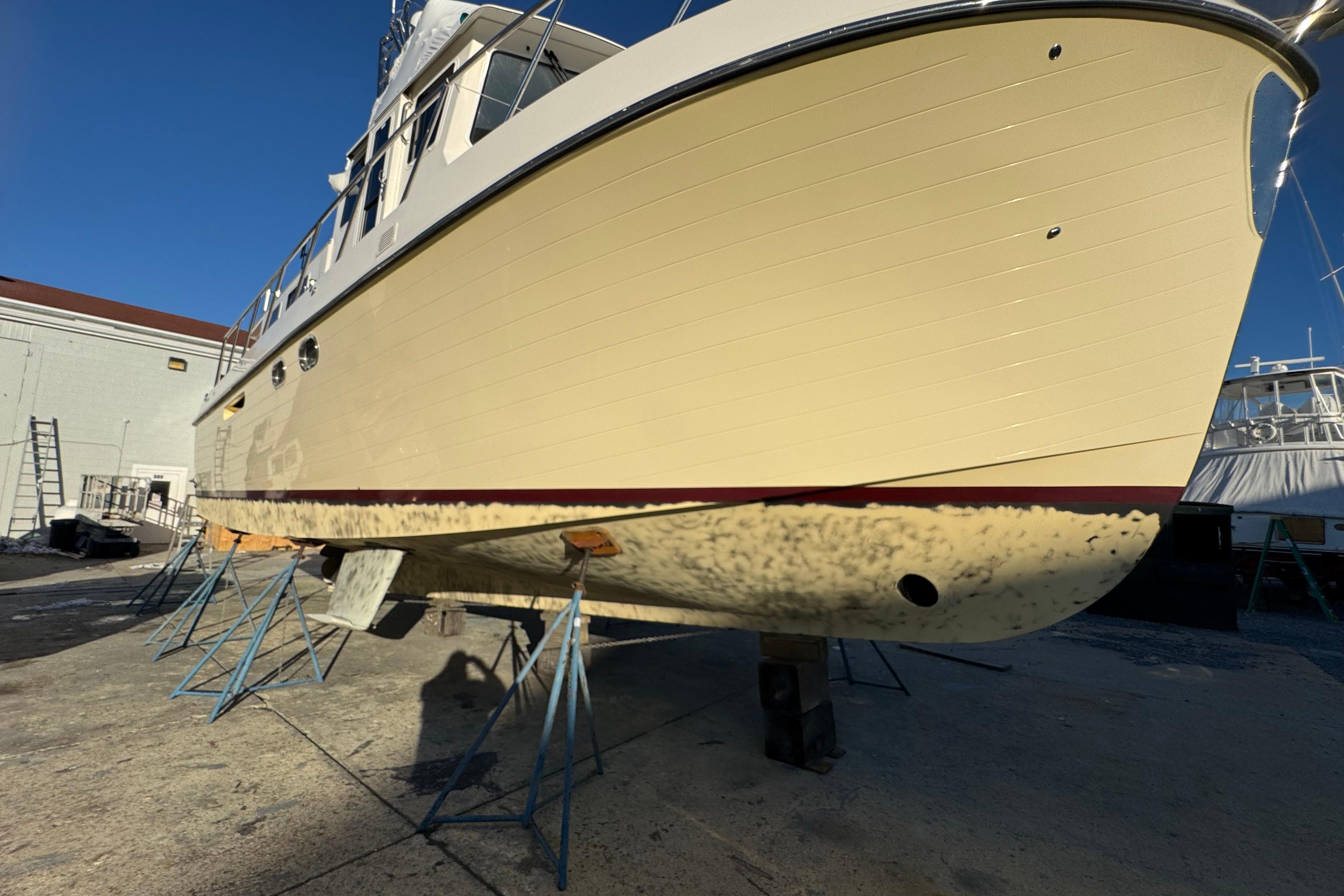 2015 American Tug 435 boat on stands in a shipyard under clear blue sky.