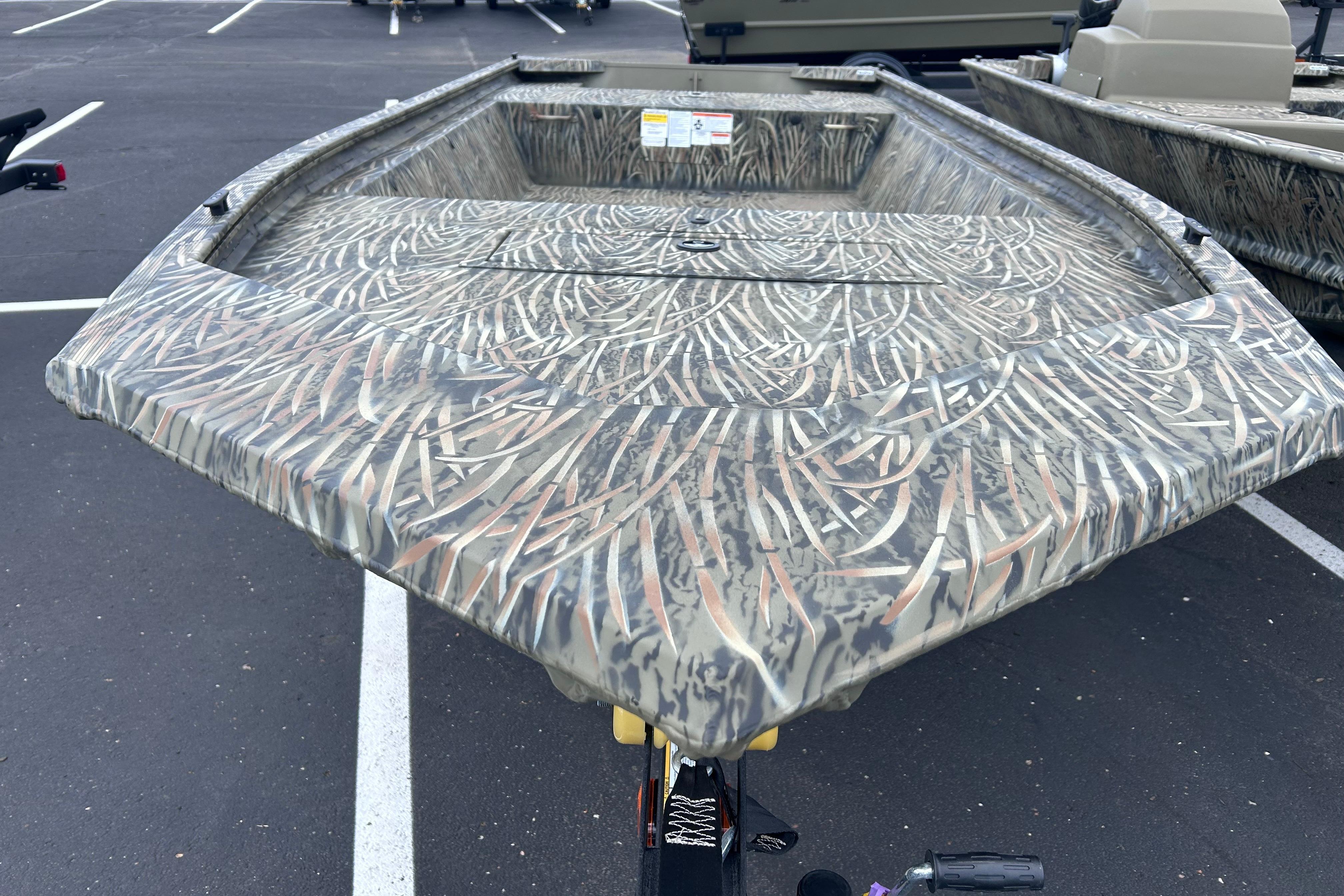 2026 Tracker Grizzly 1648 Utility boat with camouflage design in a parking lot.