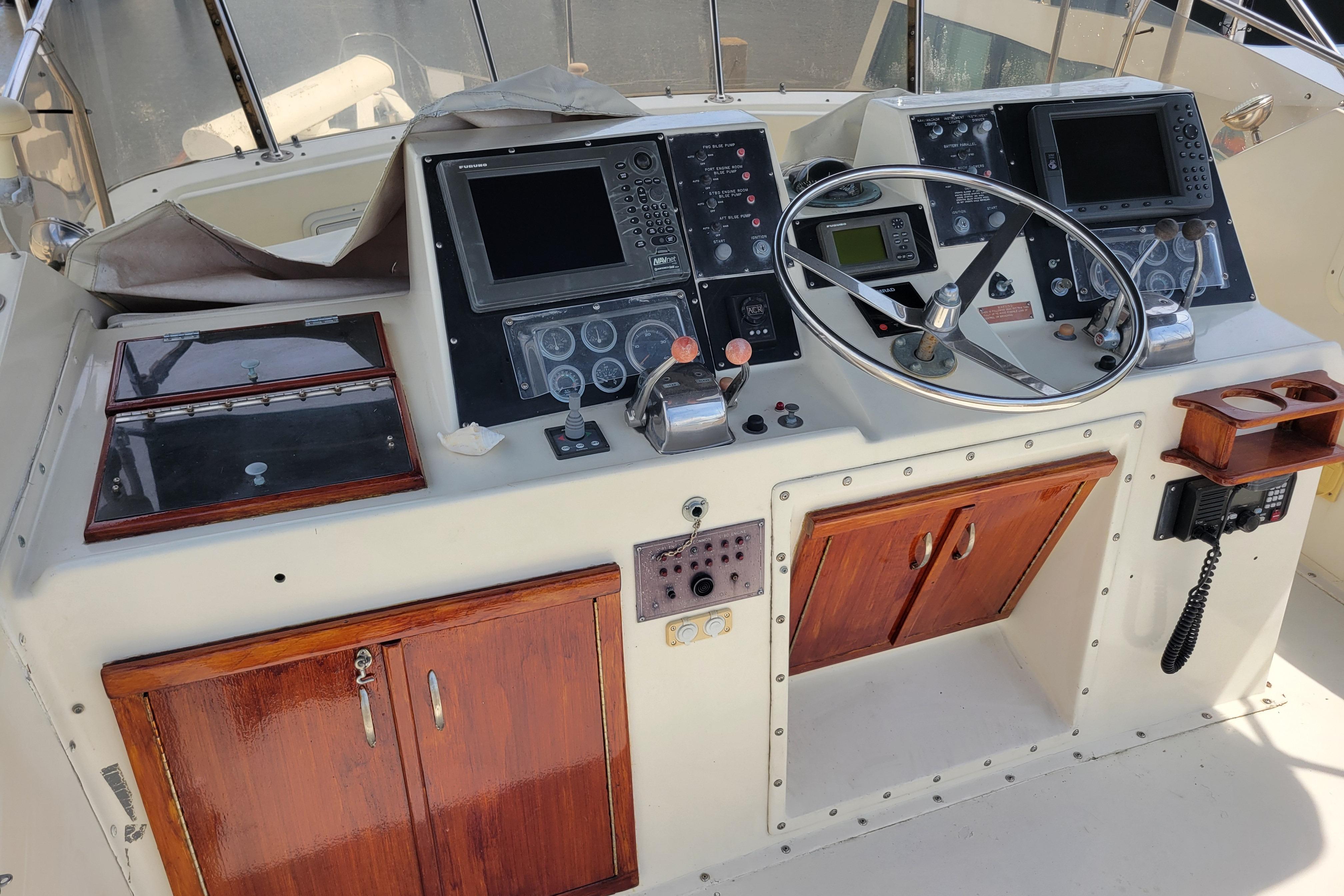 1980 Hatteras 53 Yacht Fisherman helm with navigation equipment and wooden cabinetry.