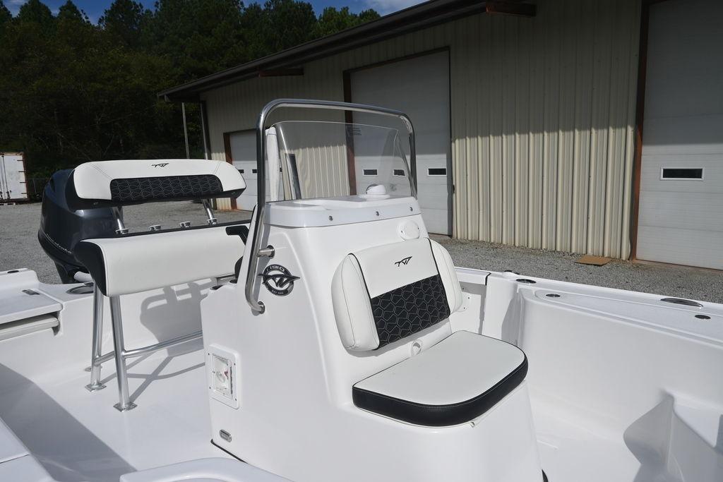 2026 Tidewater 1910 Bay Max boat interior with seating and console, parked near a building.
