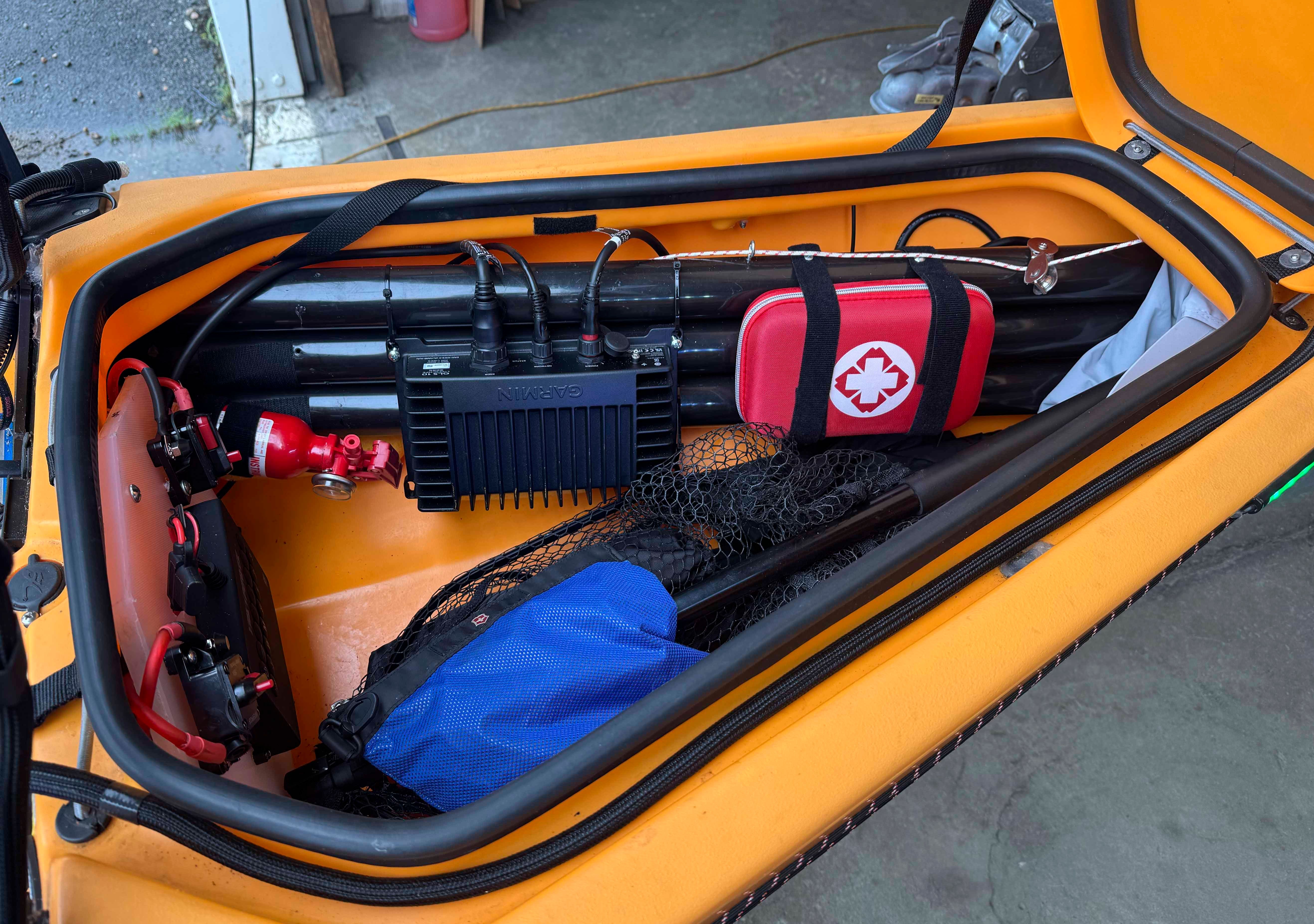 The image shows the storage area of a Hobie 14 Pro Angler Kayak with gear and a first aid kit.