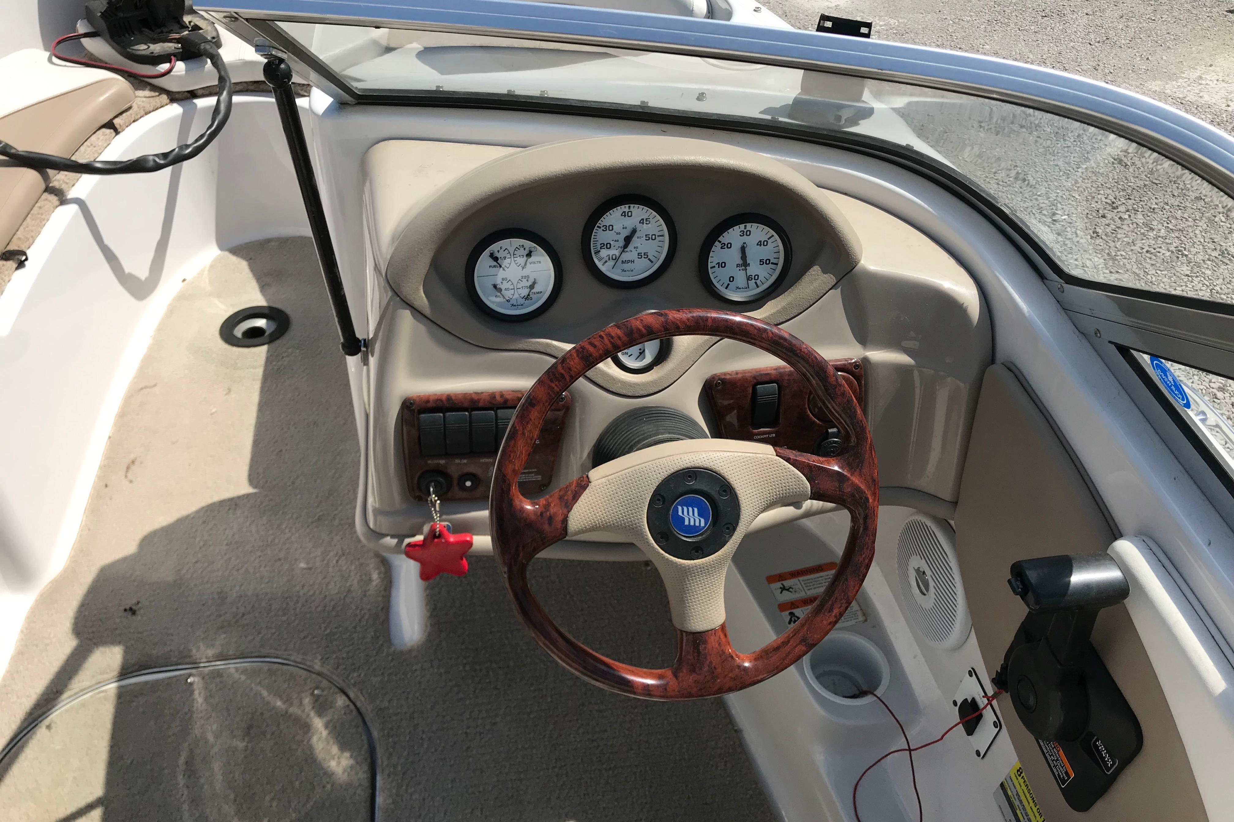 2005 Four Winns 180 Horizon FS boat dashboard with wood-accented steering wheel and gauges.