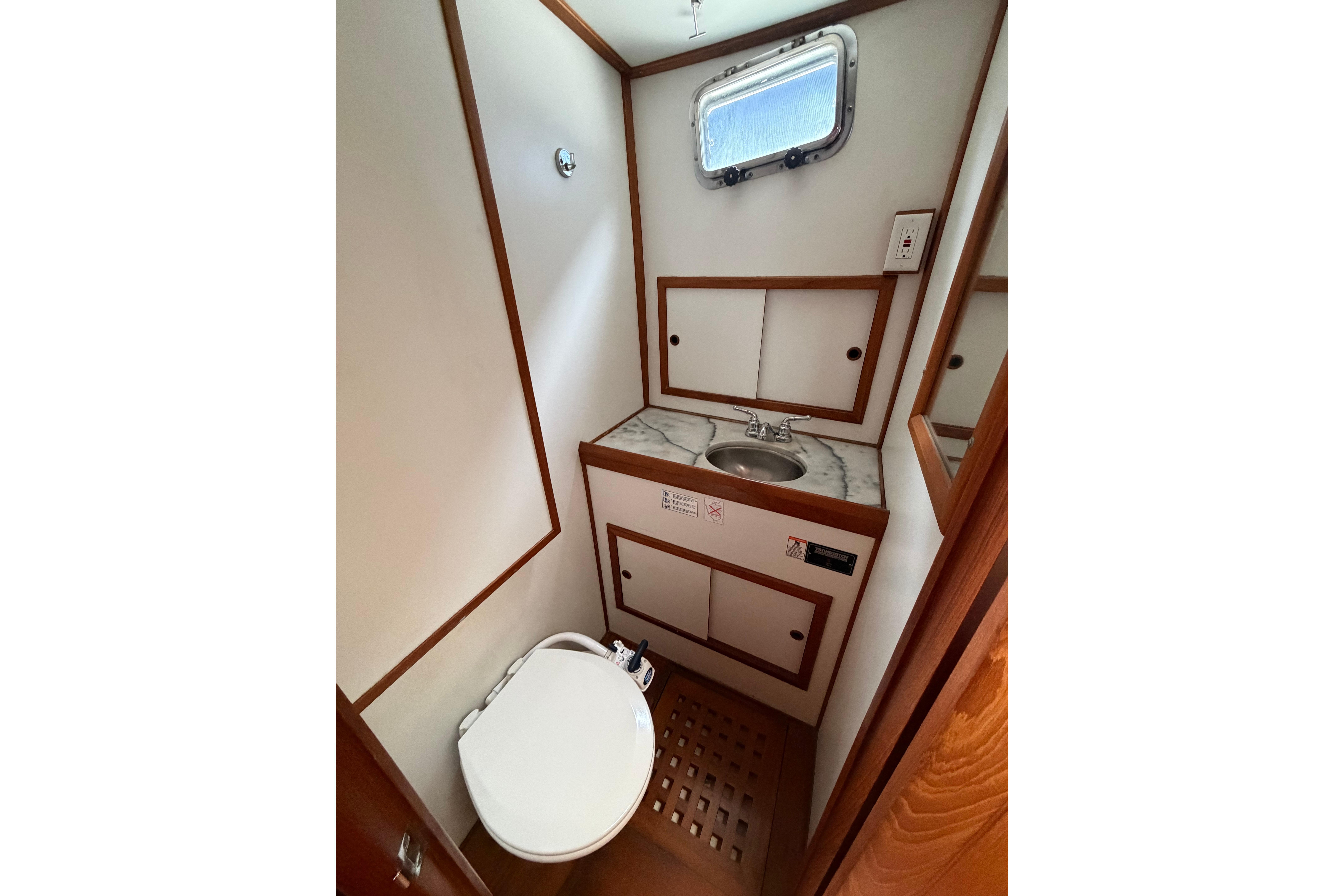 Compact bathroom in a 1988 Monk 36 boat, featuring a sink, toilet, and wooden accents.
