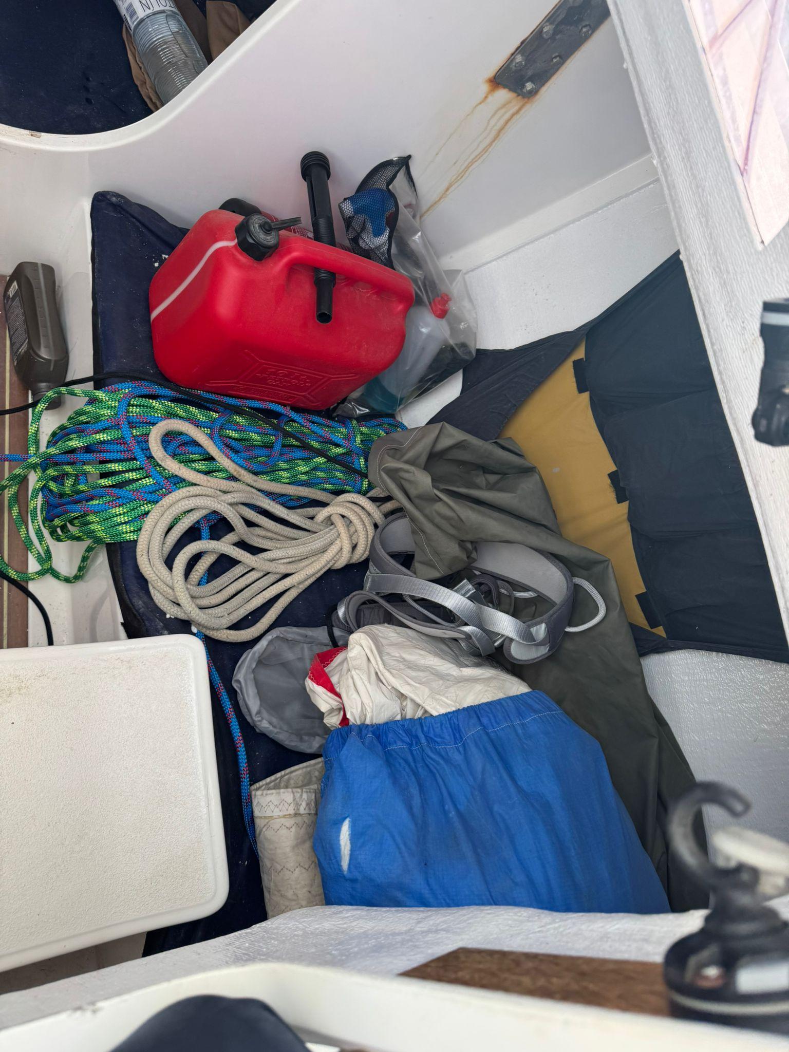 Storage compartment of a 2005 J Boats 80 with ropes, fuel can, and gear.