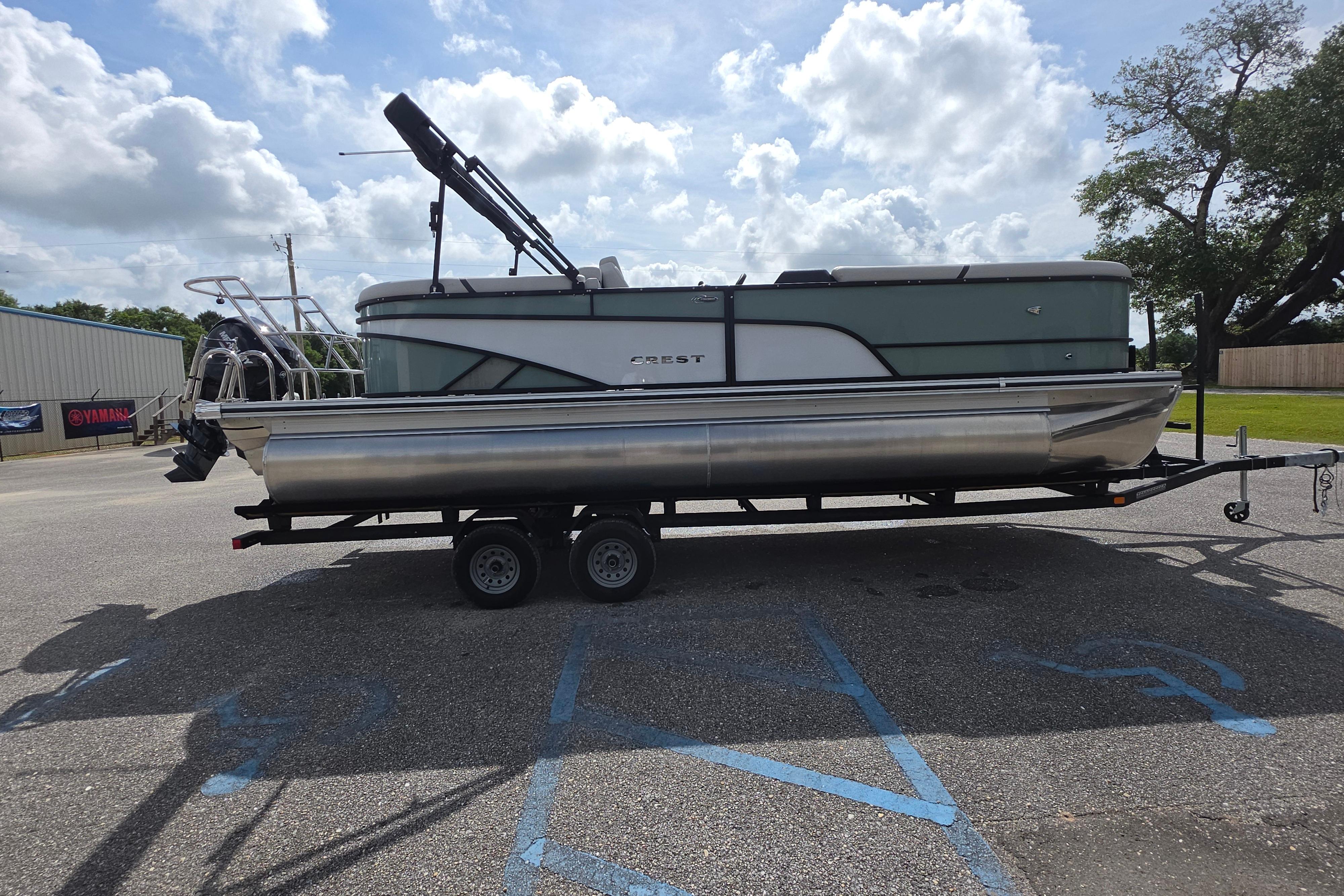 2026 Crest 235 Conquest SLC pontoon boat on trailer under cloudy sky.