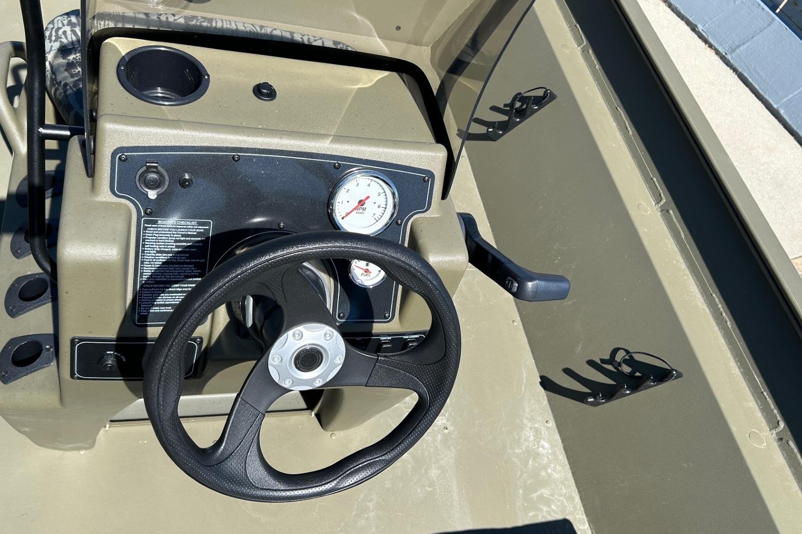 Steering console of 2026 Tracker Grizzly 2072 CC boat with gauge and cup holder.