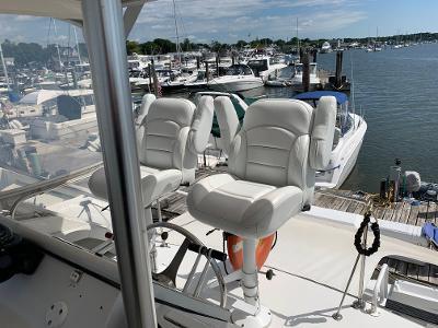 1989 Trojan 12 Meter Convertible yacht with white captain chairs at a marina.
