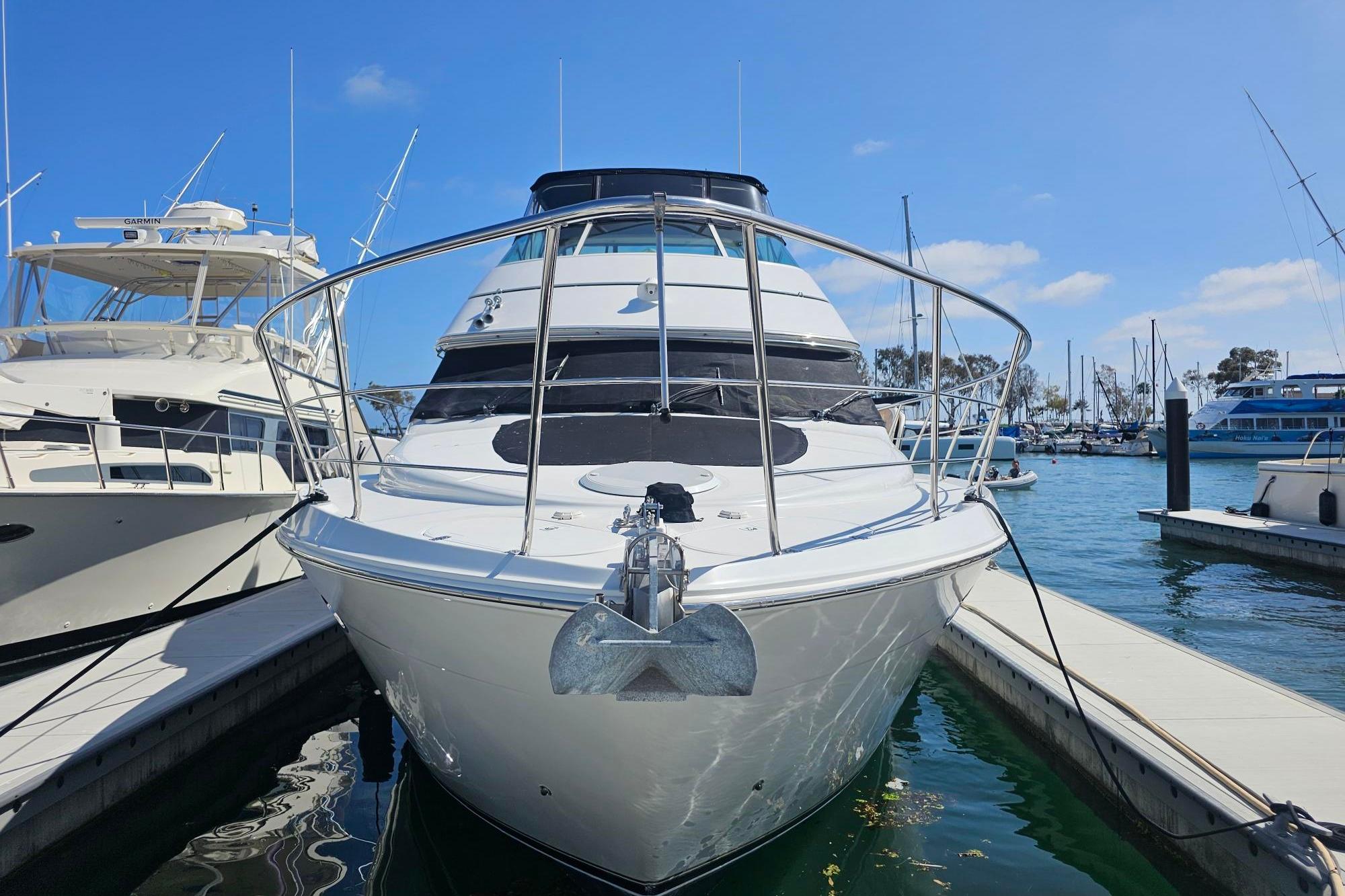 2002 Carver 450 Voyager Pilothouse yacht docked at marina under clear blue sky.