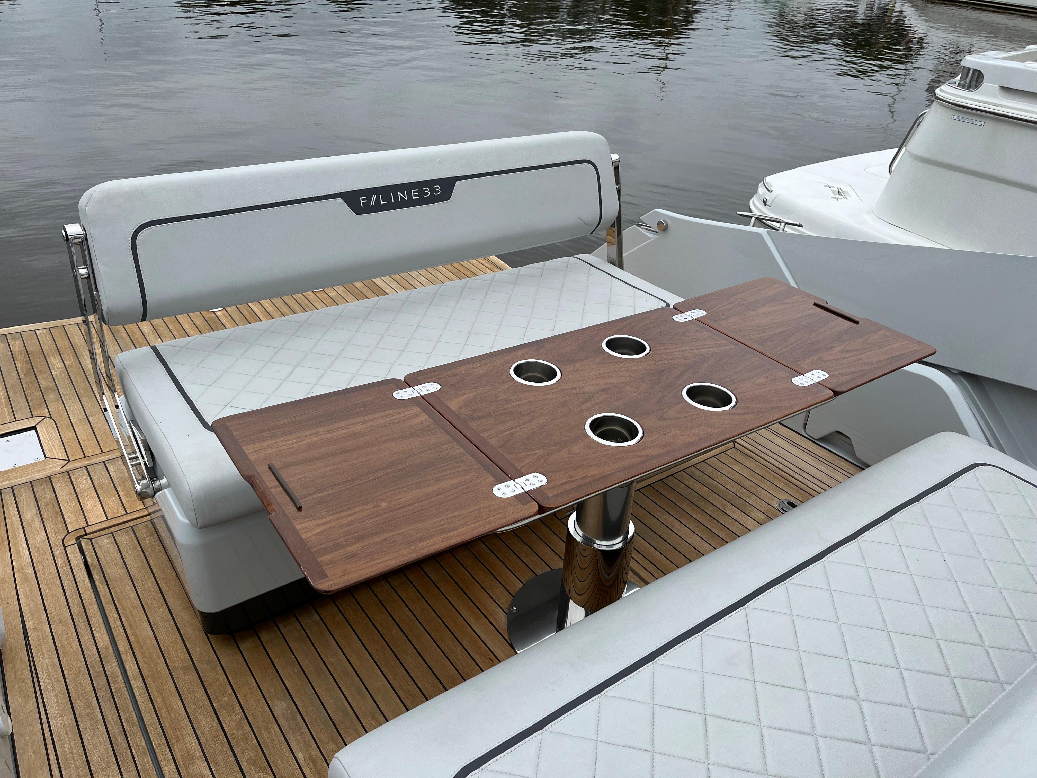 Fairline F//Line 33 yacht 2022, featuring elegant seating and a wooden table on deck.