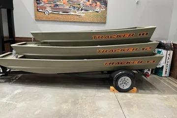 2026 Tracker Grizzly 12 Jon boats stacked on a trailer in a showroom.