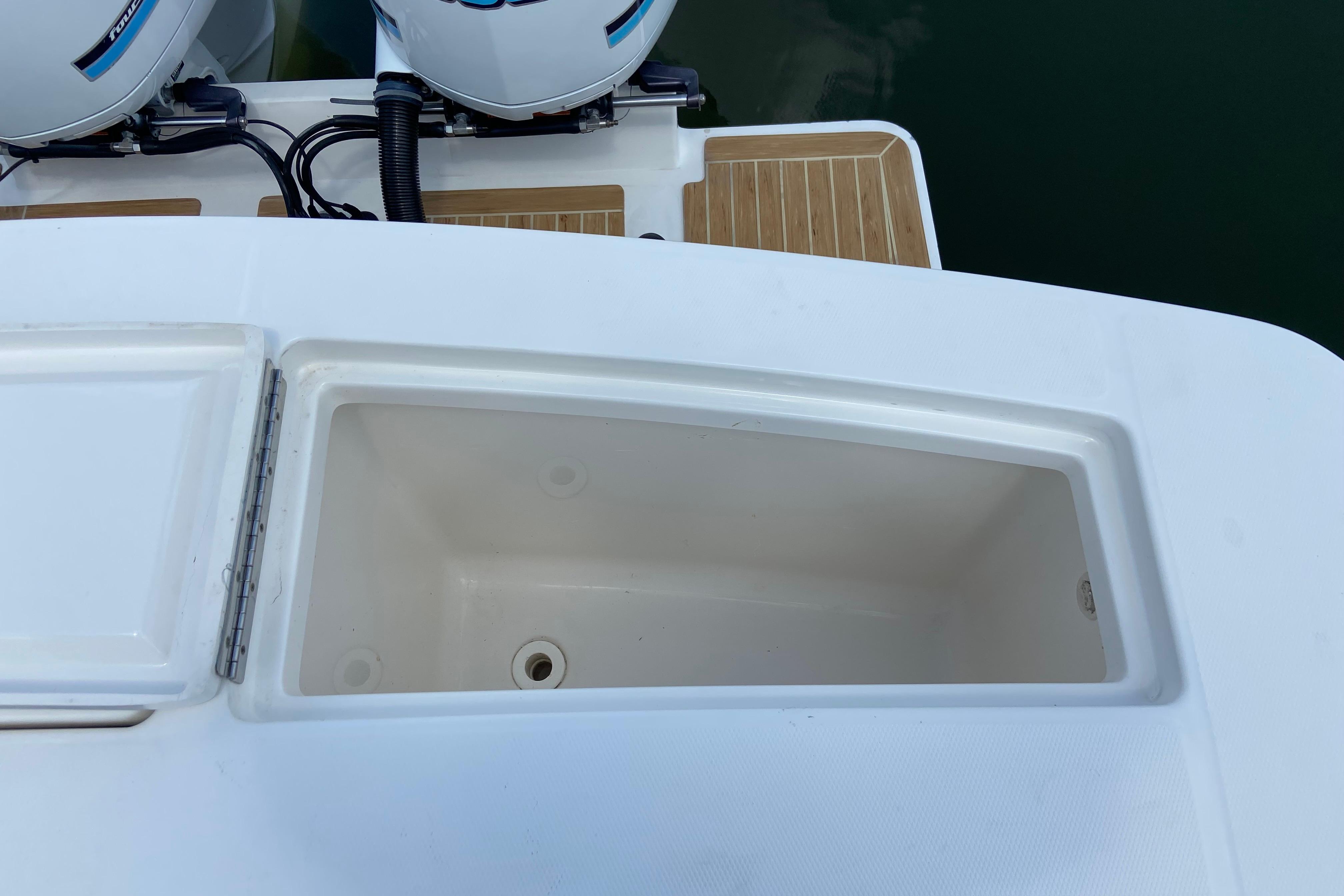 Open storage compartment on 2021 Regulator 28 boat, near twin outboard engines.