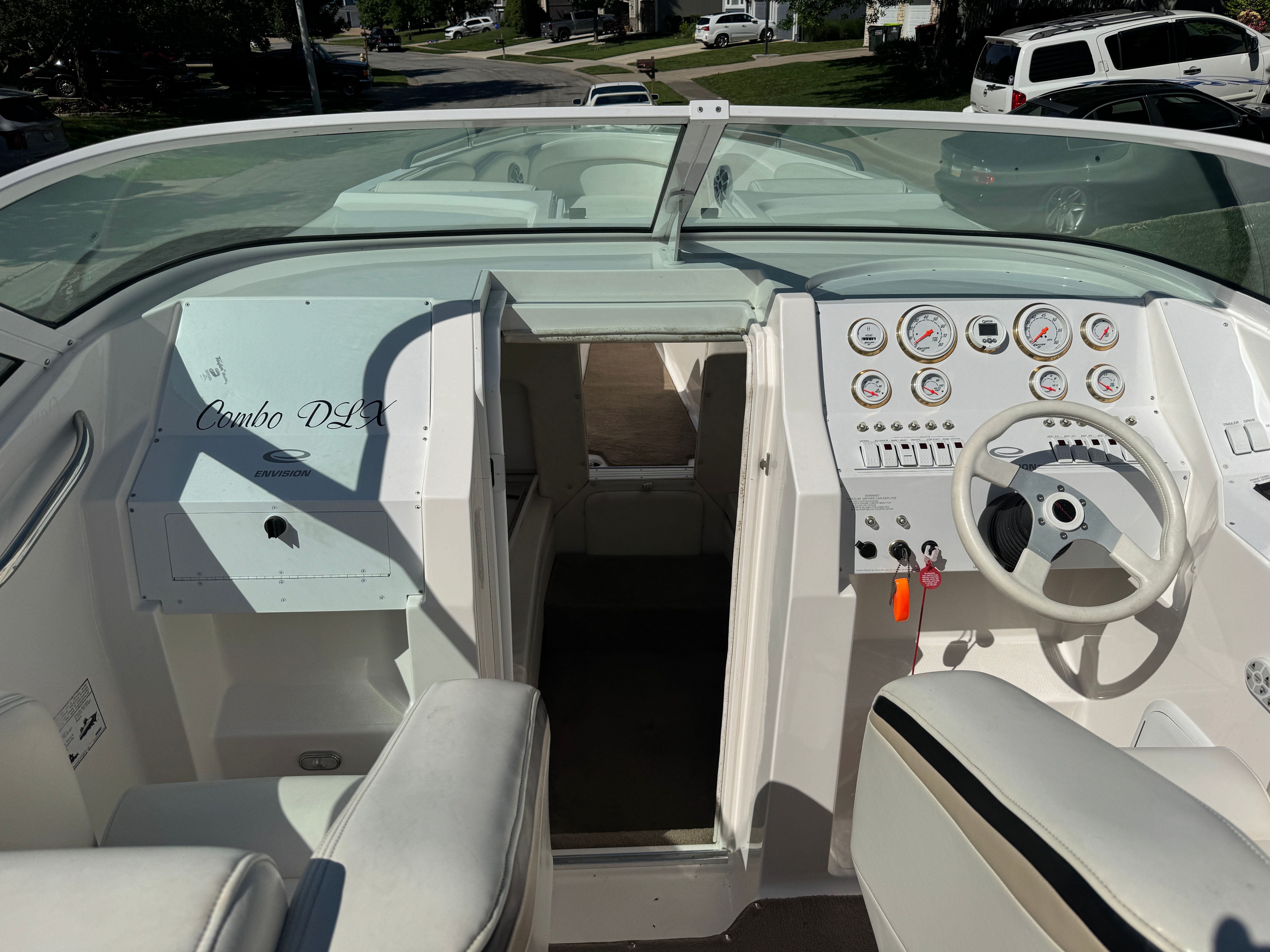 The image shows the cockpit of a 2003 Envision 2900 DLX boat with white seats and controls.