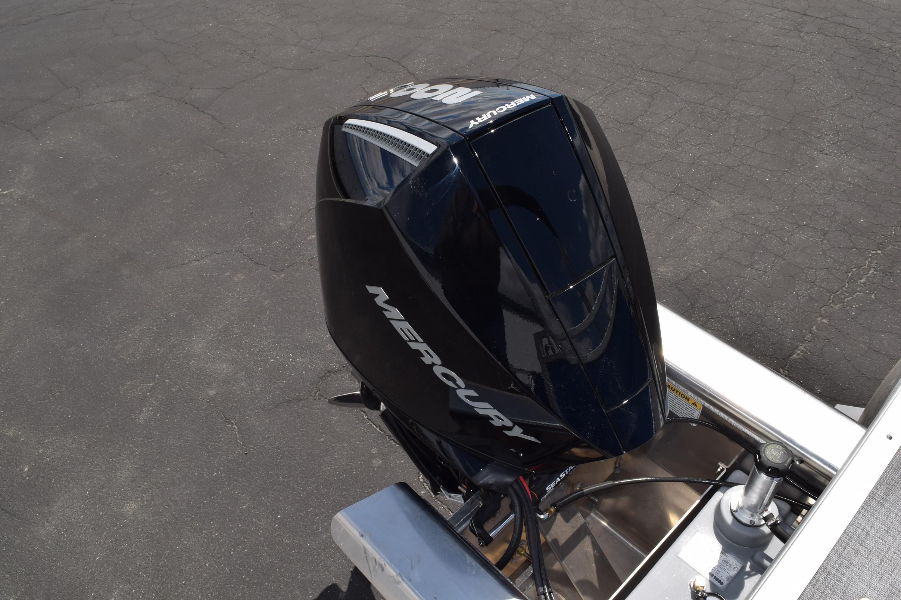Mercury outboard motor on 2026 Sun Tracker Party Barge 22 RF XP3, parked on asphalt.