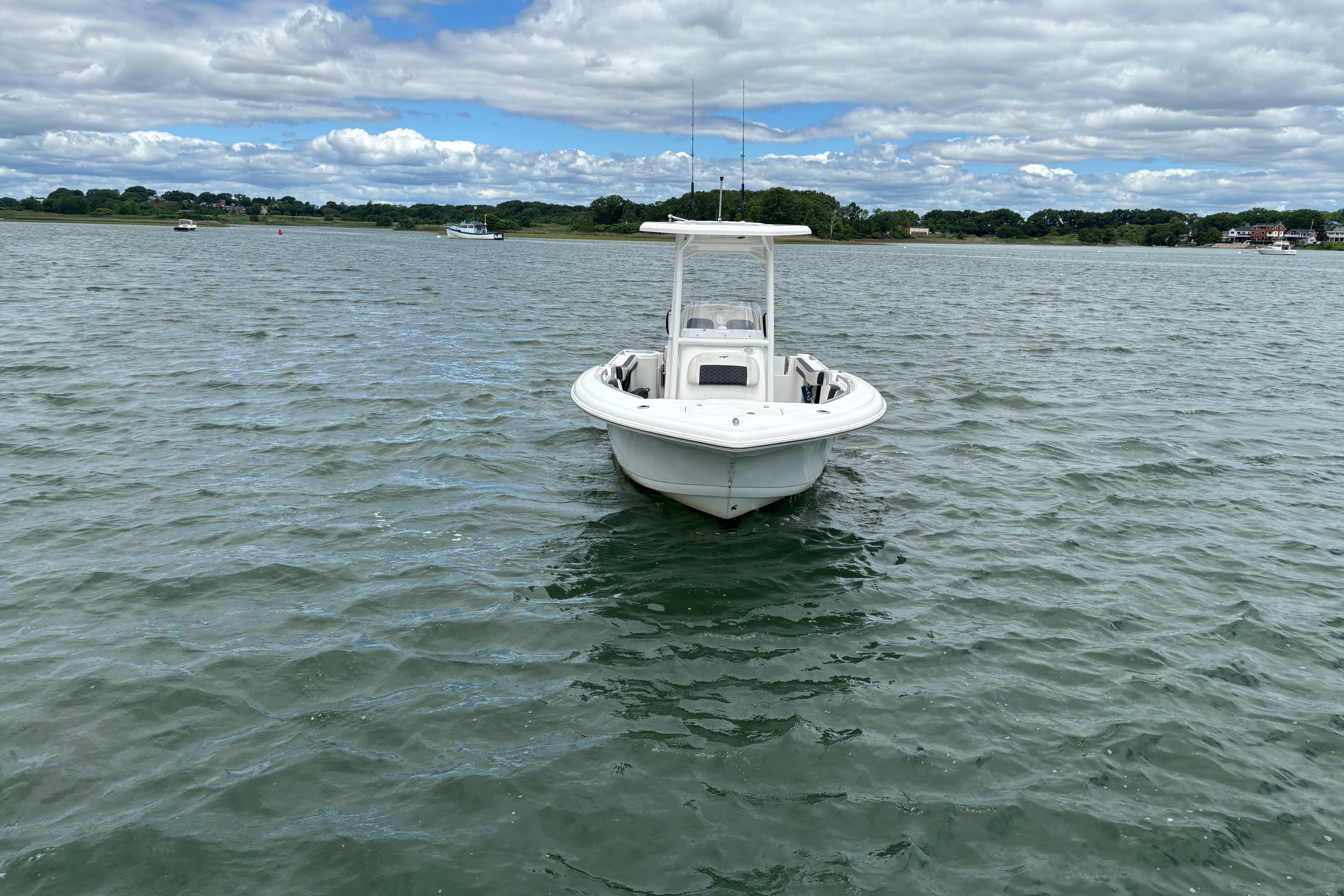 2024 Tidewater 220 CC Adventure boat on calm water under cloudy sky.