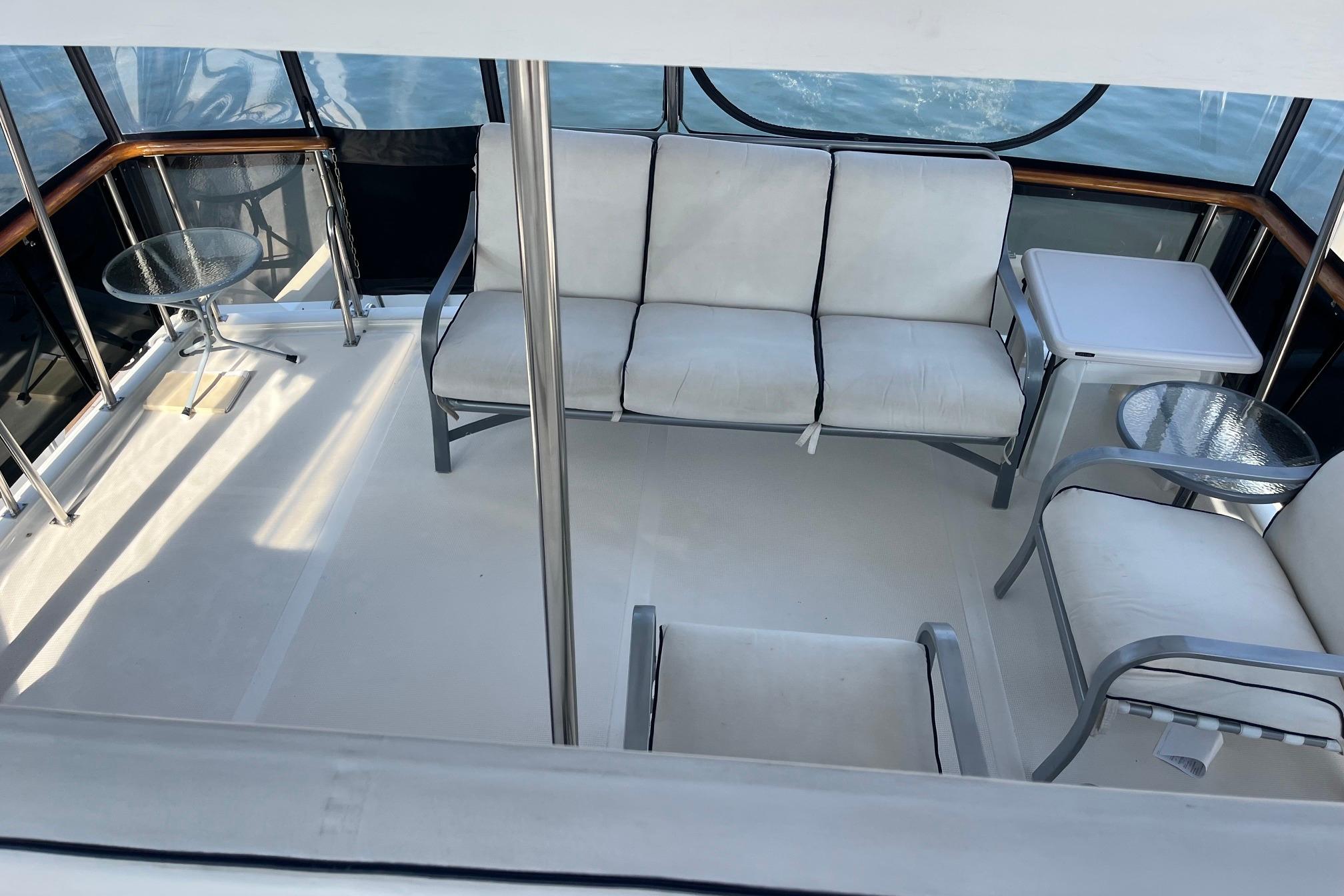 1989 Ocean Alexander 440 Sundeck CPMY interior with seating and tables on deck.