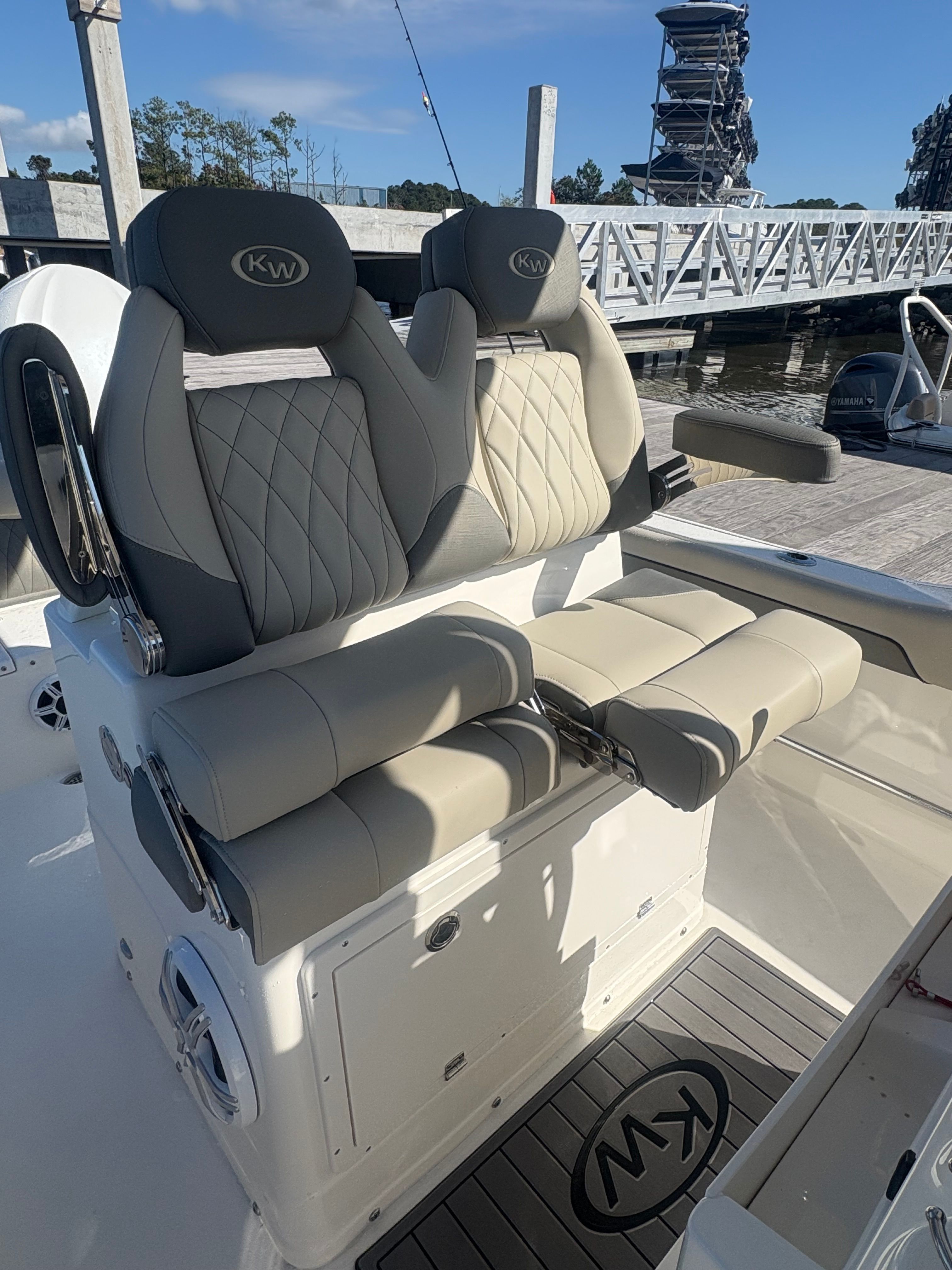 Two luxurious seats on a modern boat, featuring quilted leather and armrests.