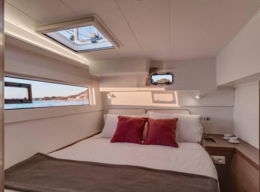 Luxurious 2024 Lagoon 40 yacht cabin with scenic ocean view and elegant bedding.