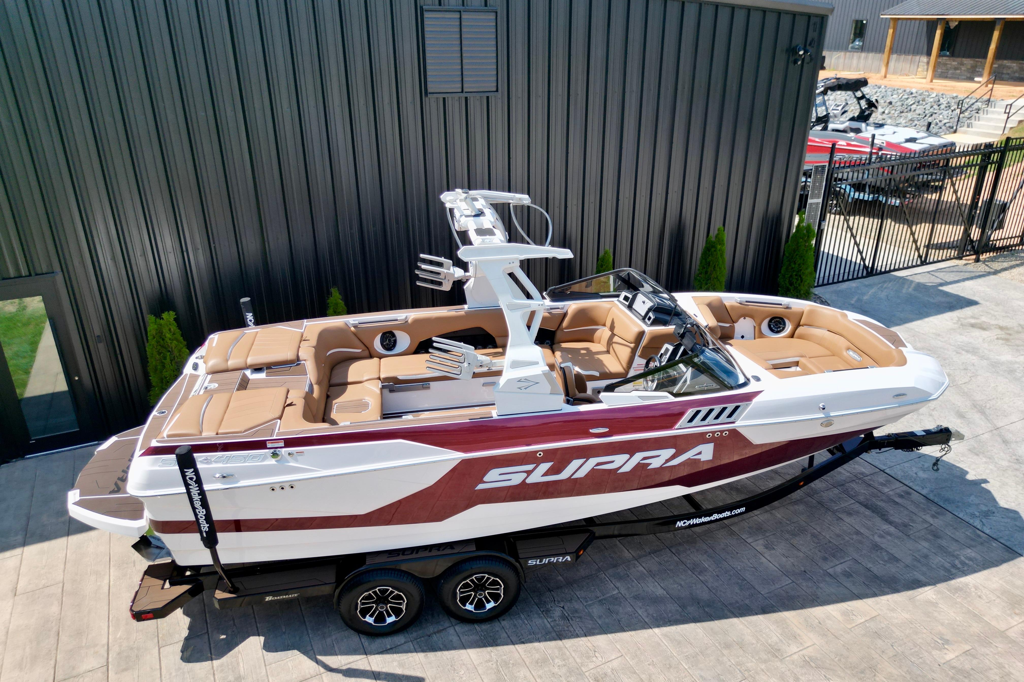 2021 Supra SE boat with sleek design, parked on a trailer near a modern building.