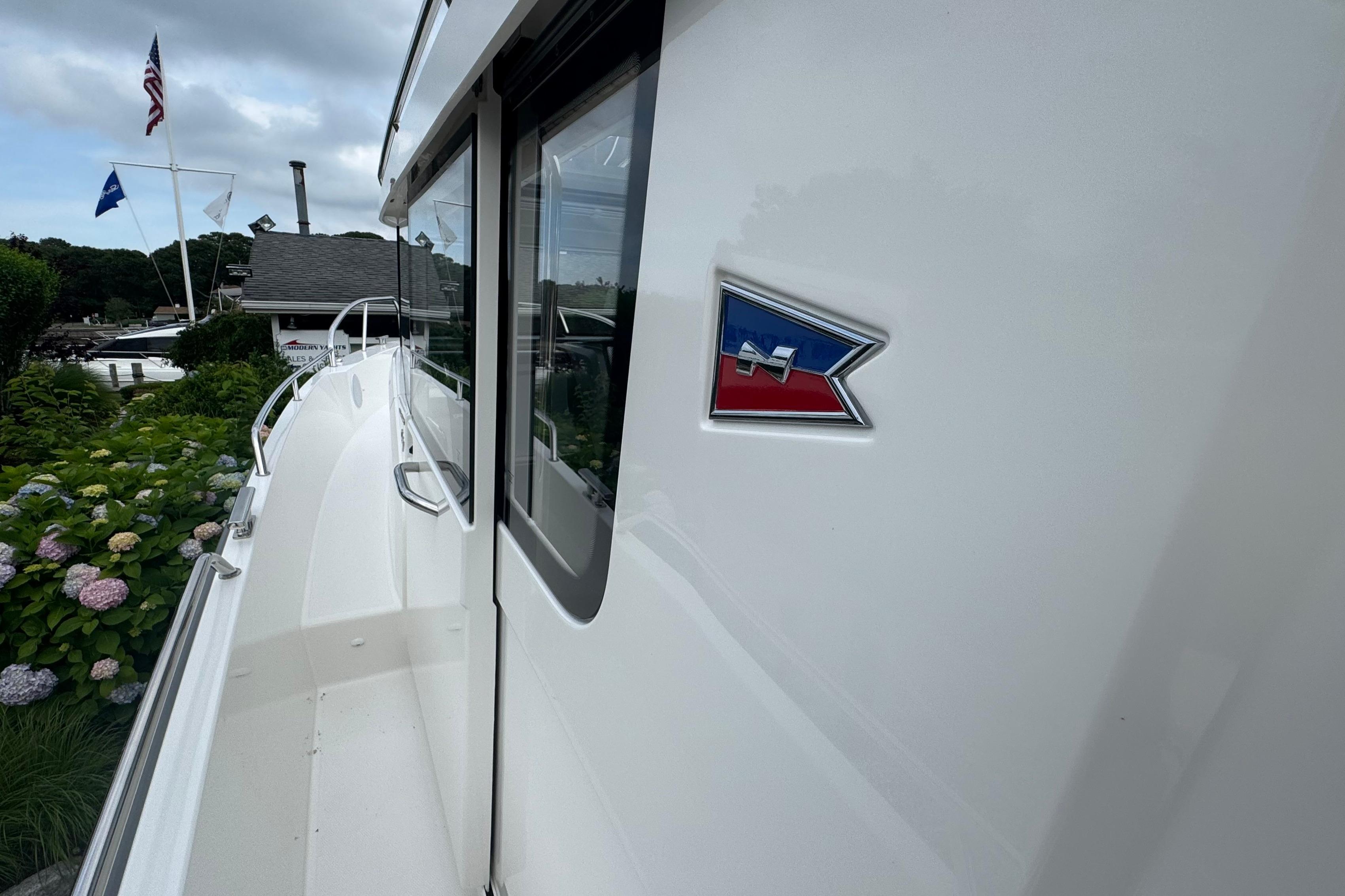 Side view of a Nimbus Commuter 9 boat with flag emblem, manufactured in 2026.