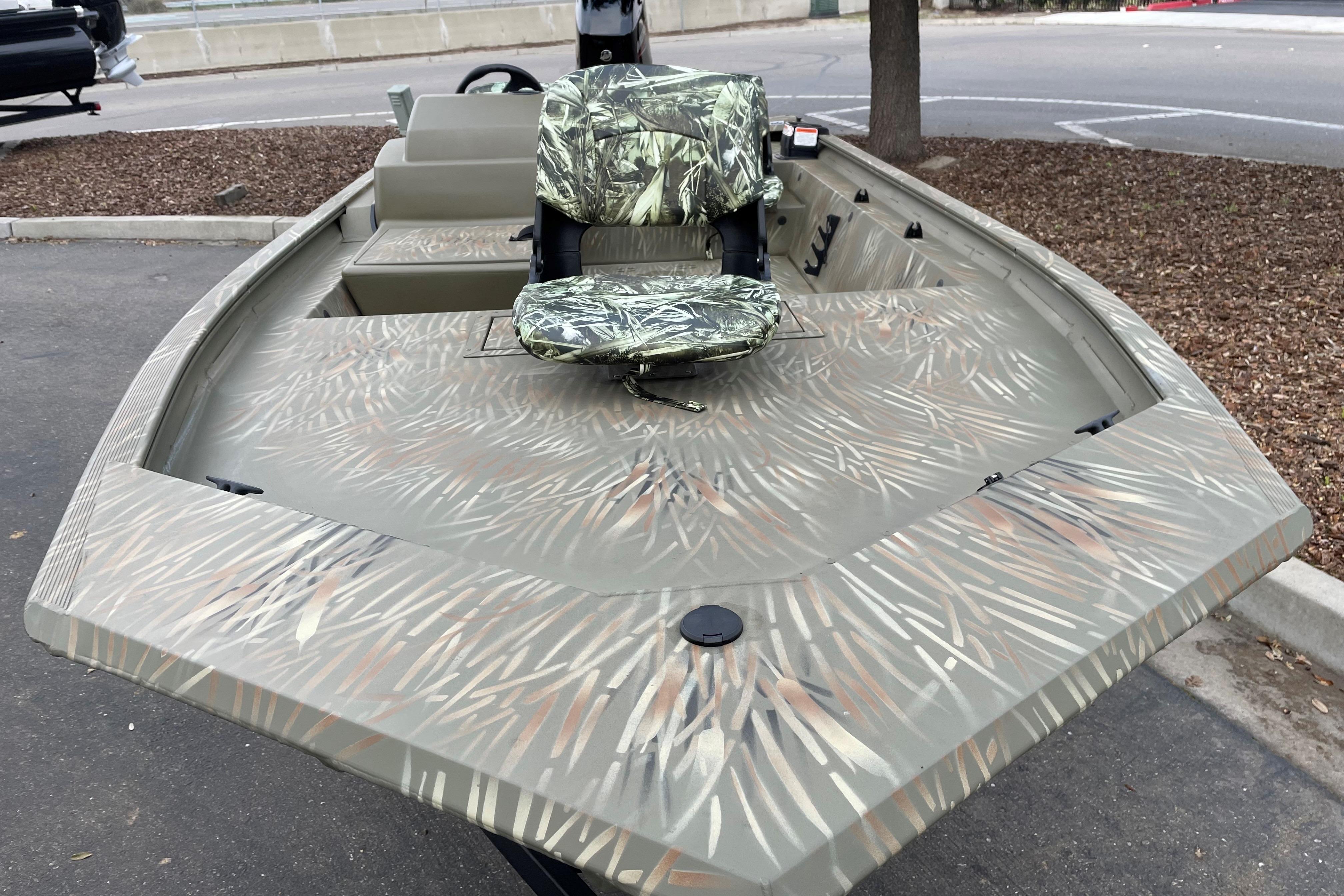 2025 Tracker Grizzly 1754 SC boat with camouflage design, parked outdoors.