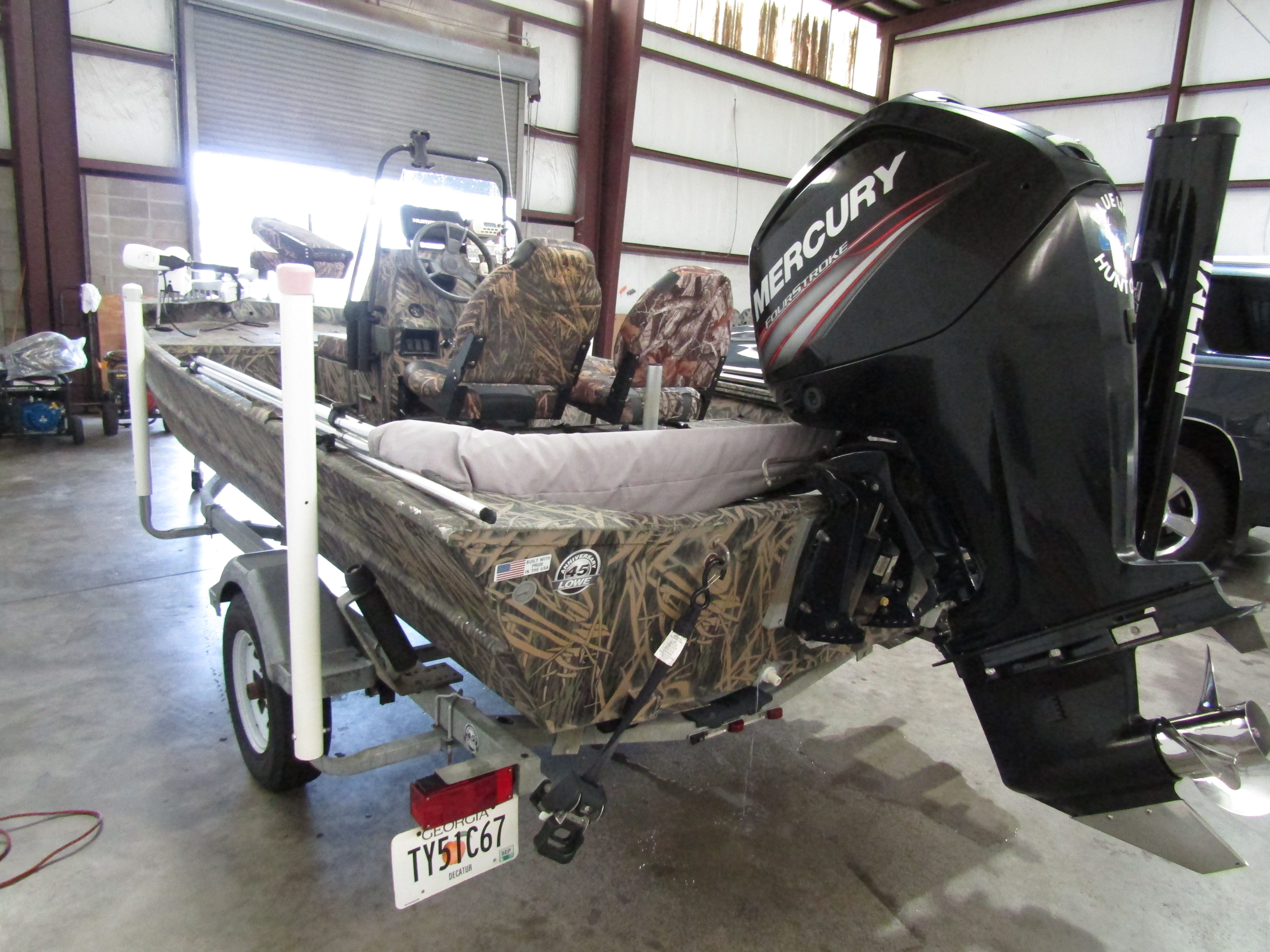 A 2016 Lowe 186 boat with a Mercury outboard motor, on a trailer in a warehouse.