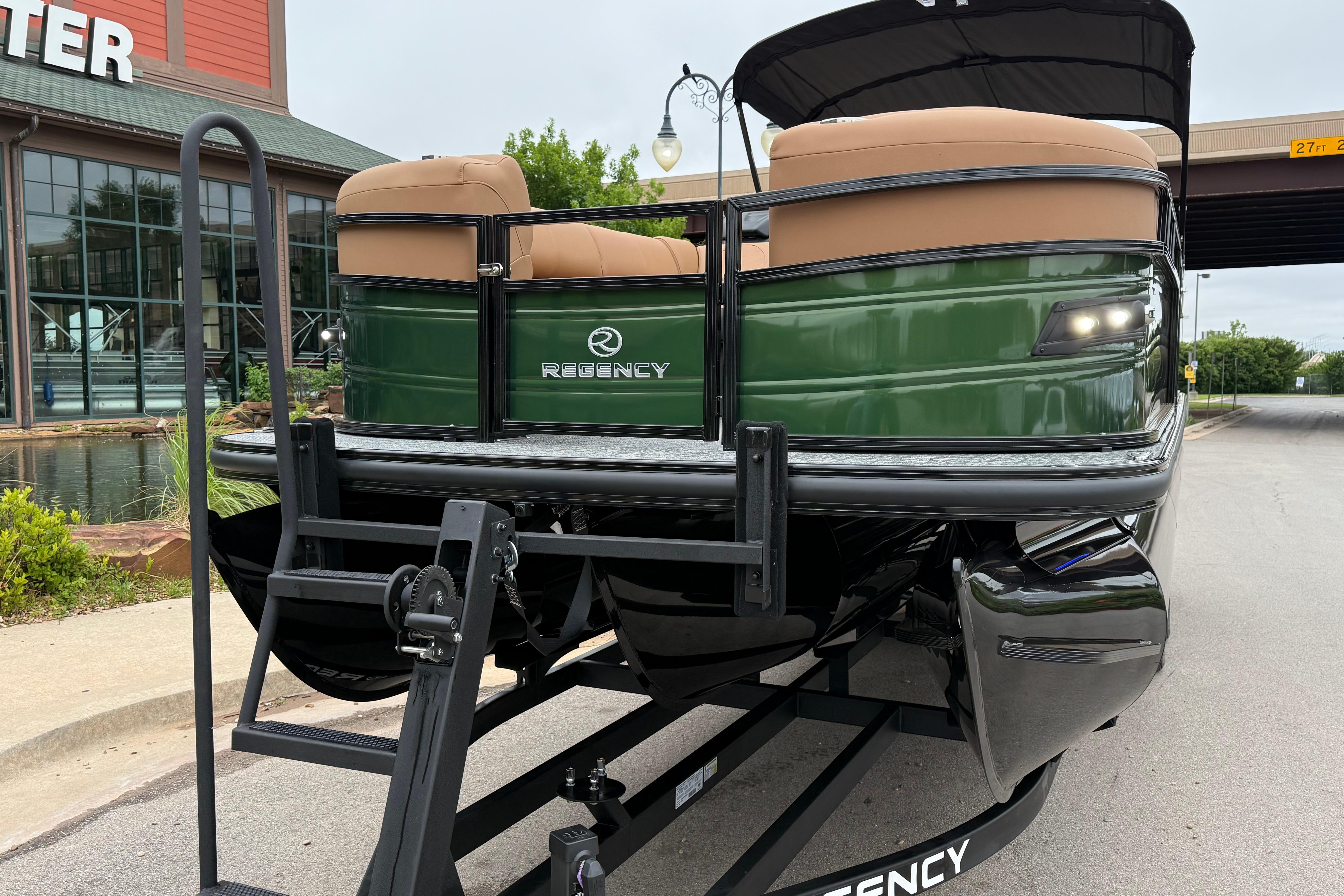2026 Regency 250 DL pontoon boat on trailer, green exterior, parked near a building.