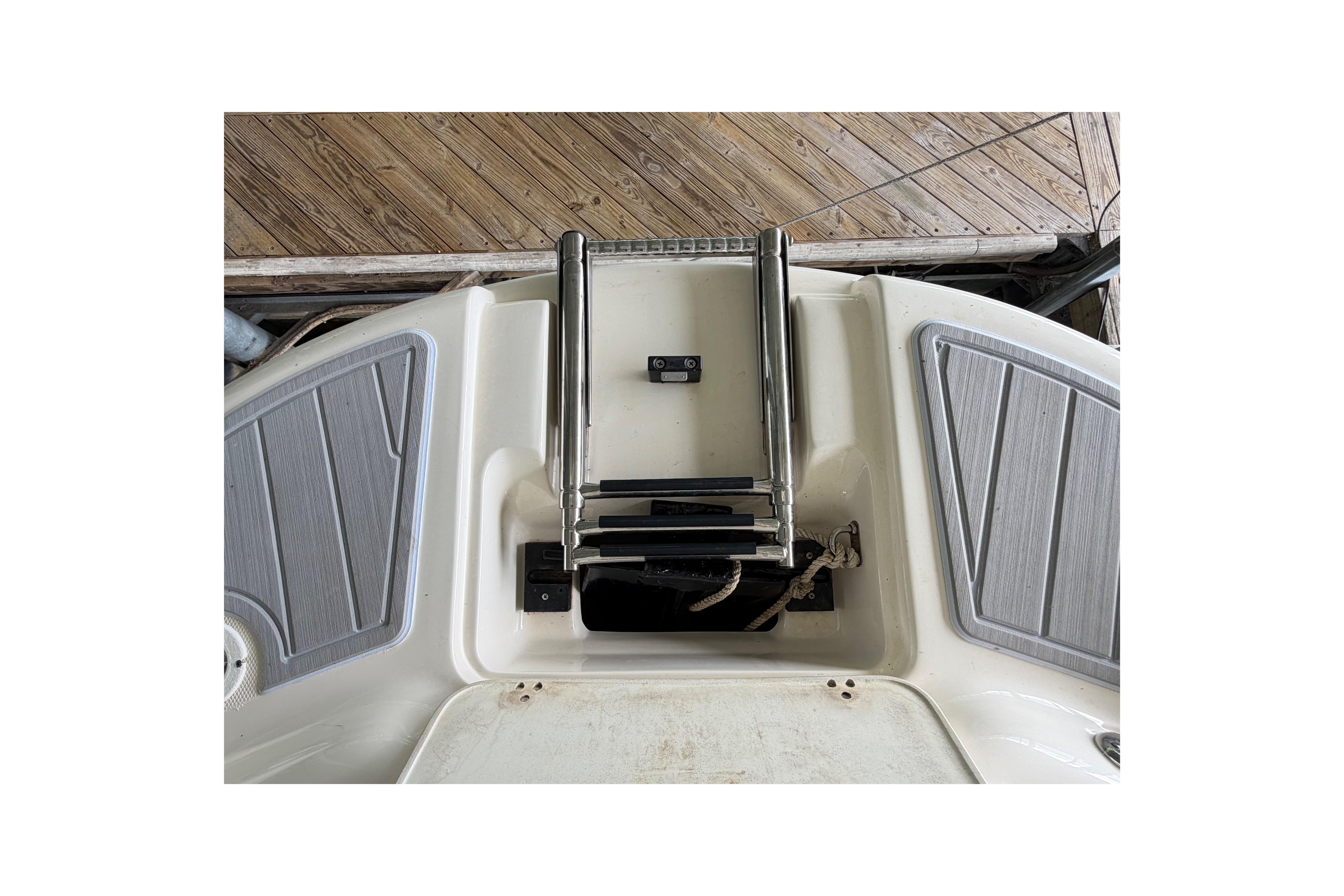 2010 Bryant 255 boat swim platform with foldable ladder and wooden dock background.