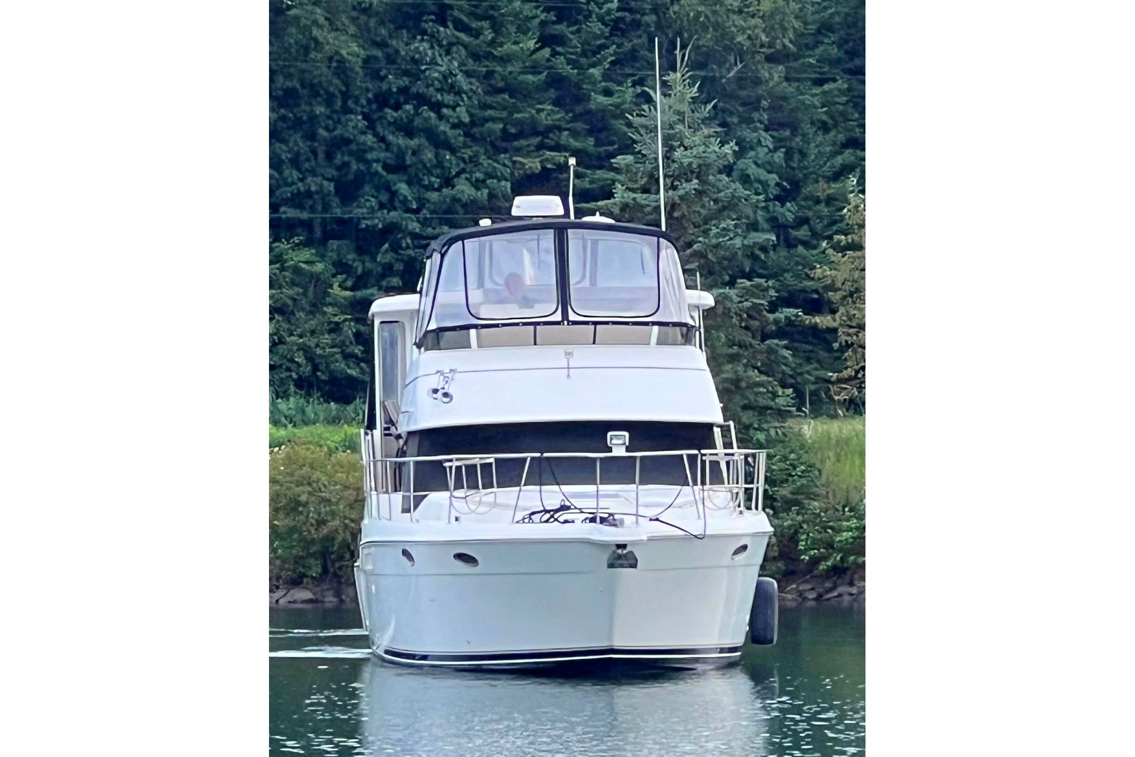 1998 Carver 355 Aft Cabin Motor Yacht on tranquil water, surrounded by lush greenery.