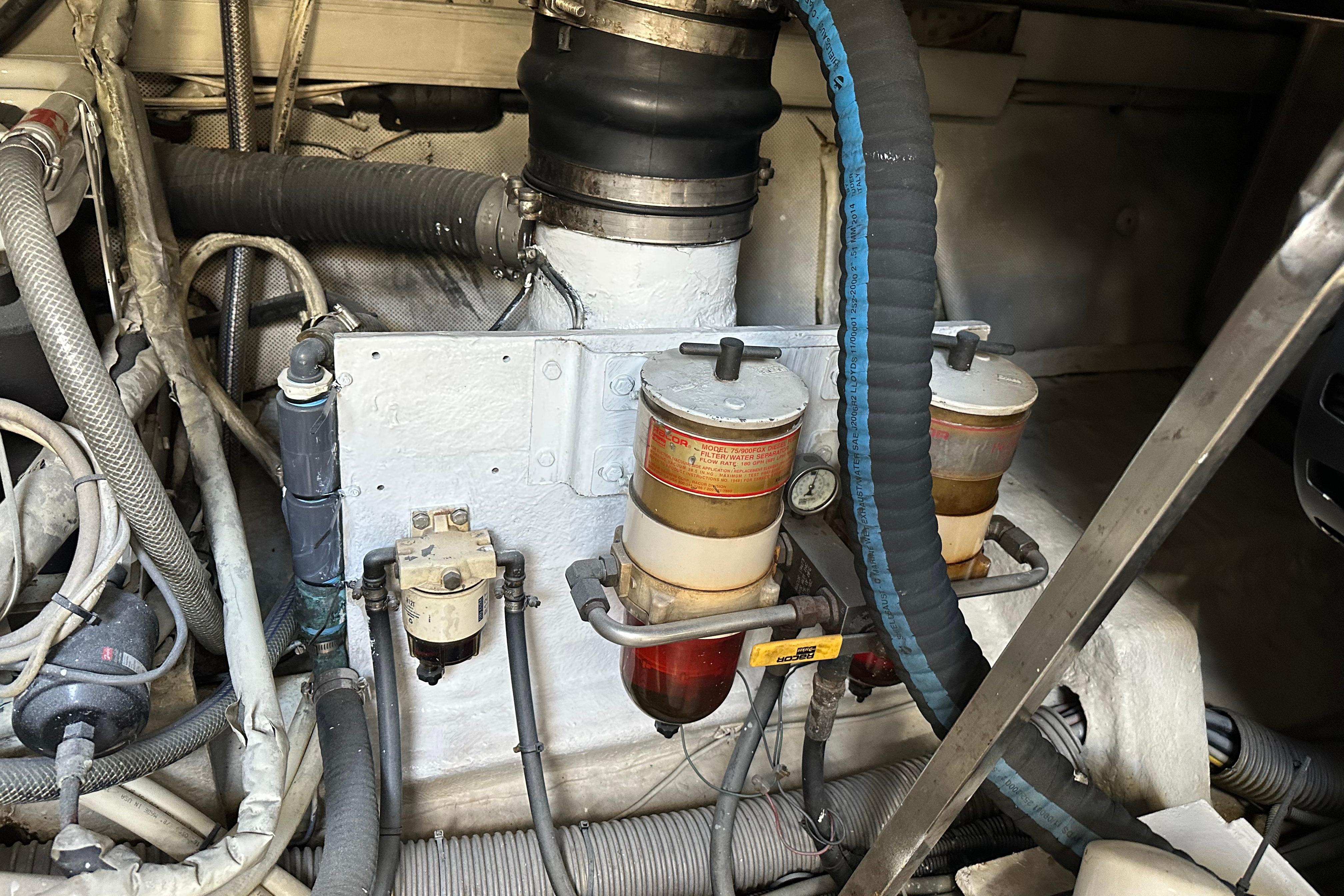 Engine room of a 2004 Azimut 55E yacht, showcasing fuel filters and hoses.