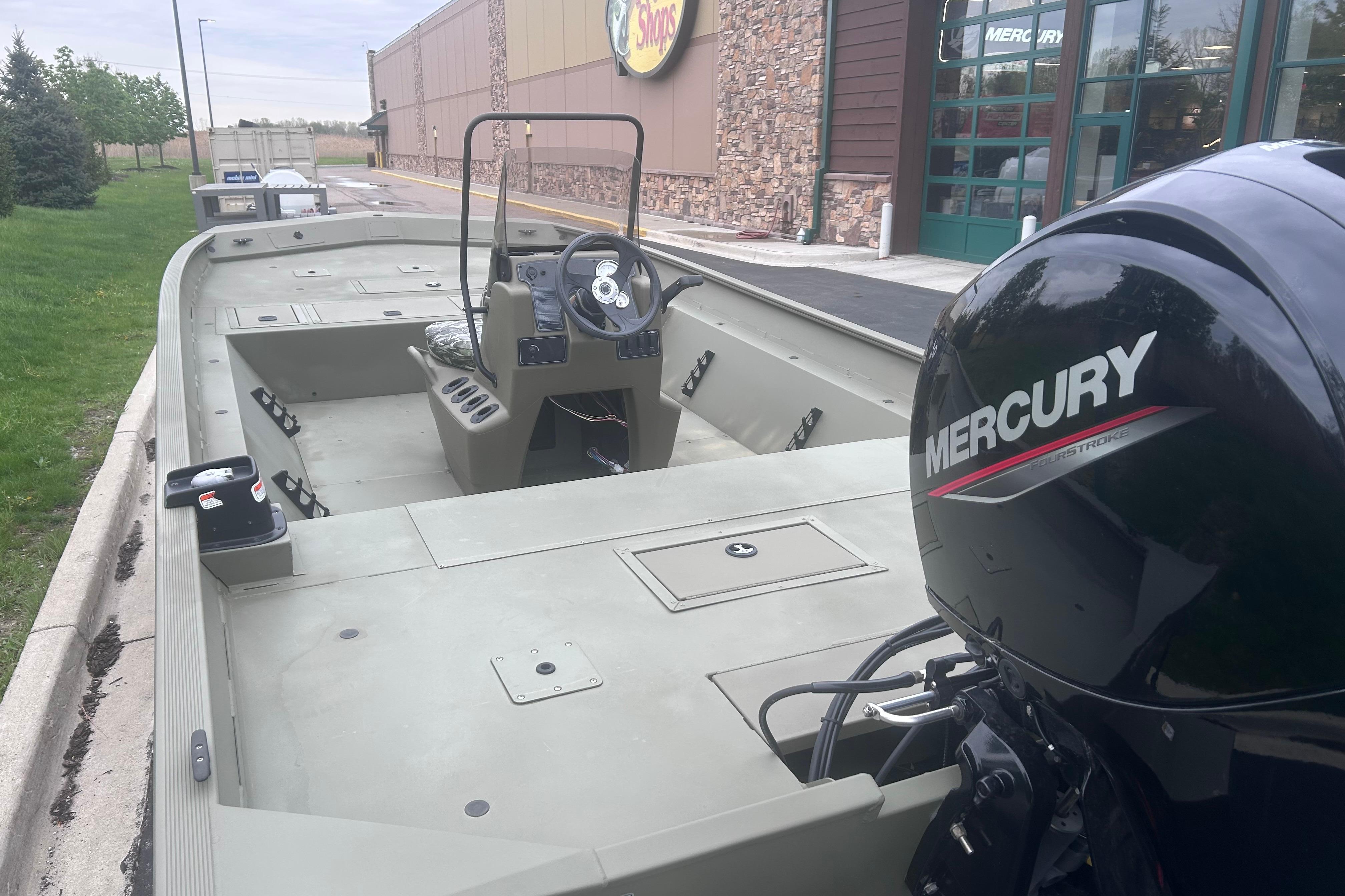 2024 Tracker Grizzly 2072 CC boat with Mercury engine, parked outside a store.
