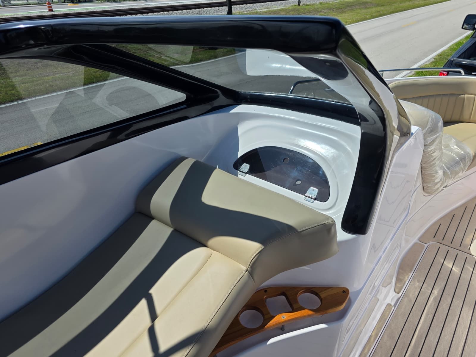 The image shows the cockpit of a Coral 26 boat with beige seating and wood accents.