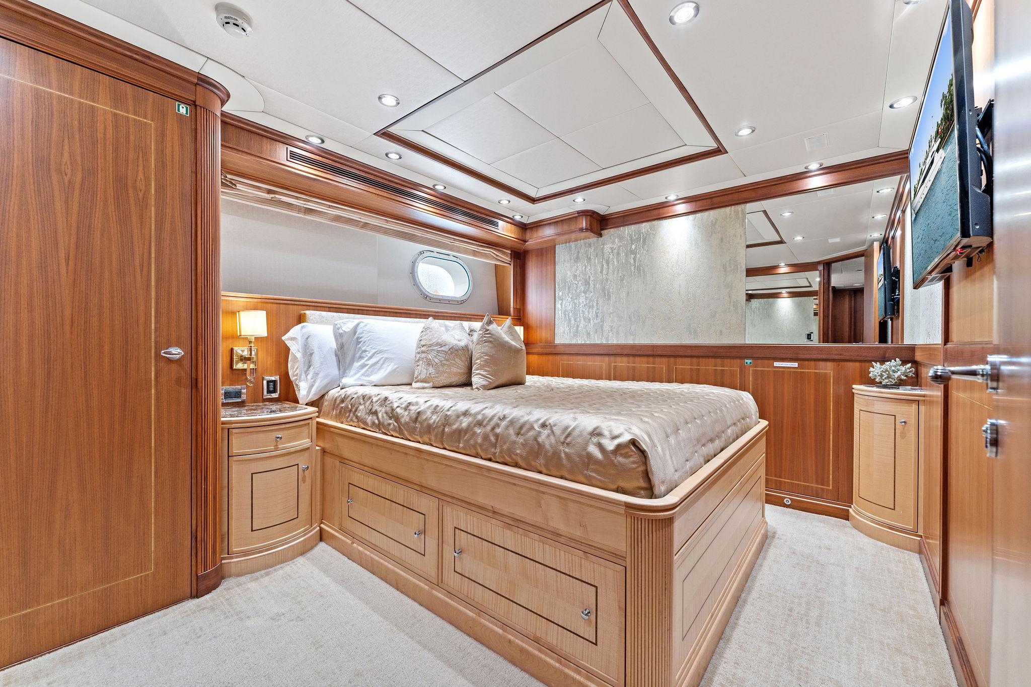 Luxurious 2006 Palmer Johnson motor yacht bedroom with elegant wood paneling and cozy bedding.