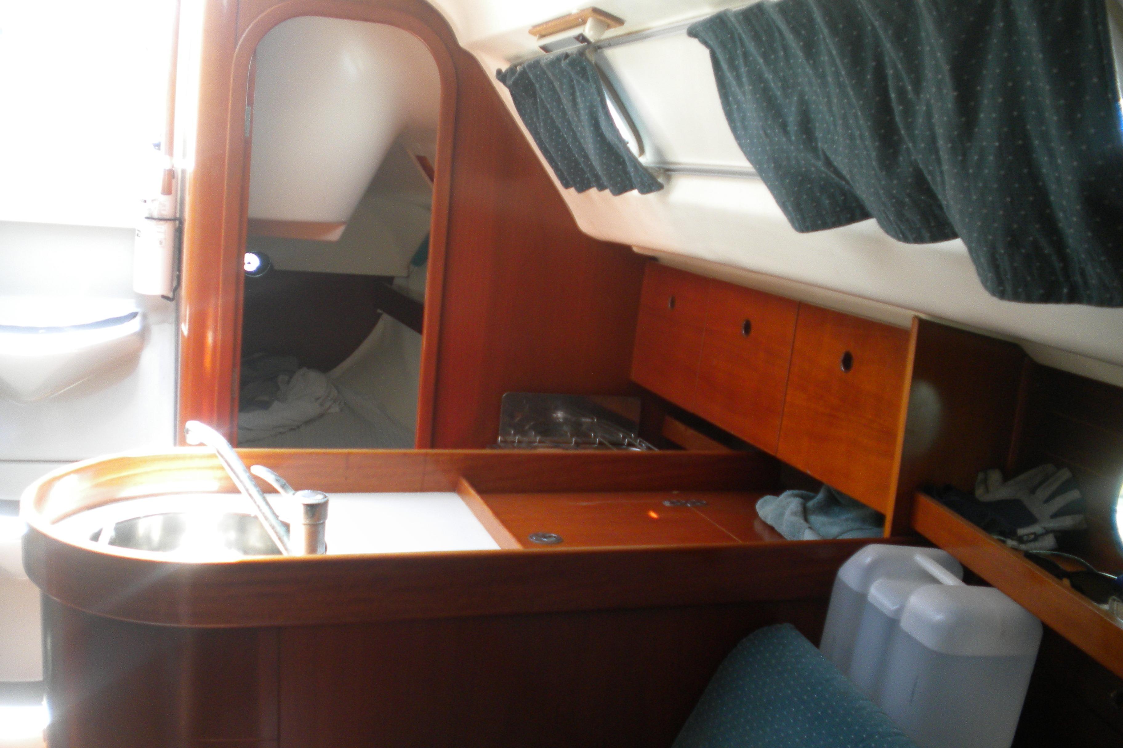 Interior of 1994 Beneteau First 310 sailboat with wooden cabinetry and compact kitchen area.