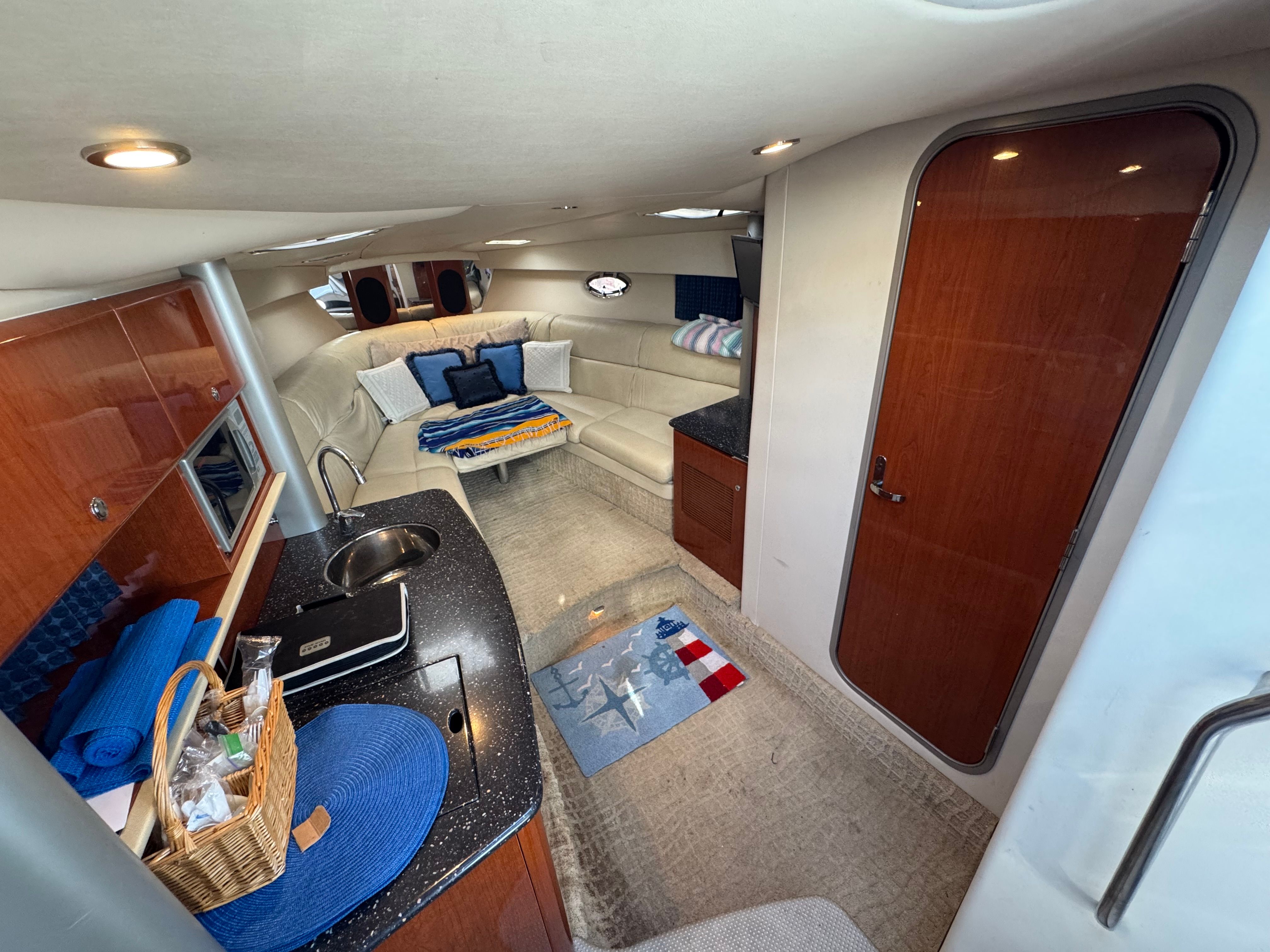 Interior of a luxury yacht with seating area, kitchenette, and wooden doors.