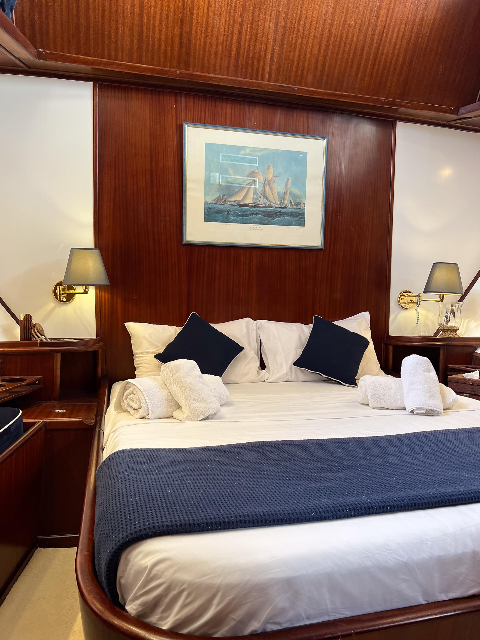 Luxurious cabin interior on a 1969 Psarros Shipyard yacht, featuring elegant wood paneling and cozy bedding.