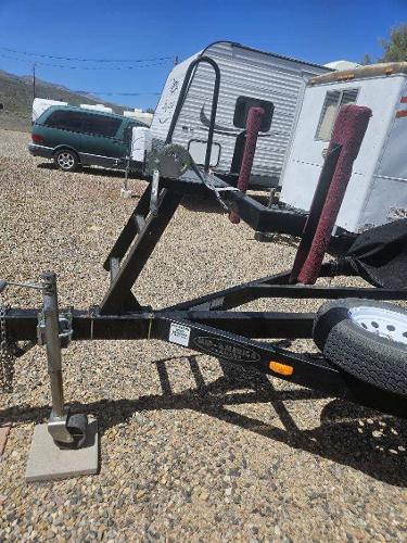 A boat trailer is parked on a gravel lot next to campers.