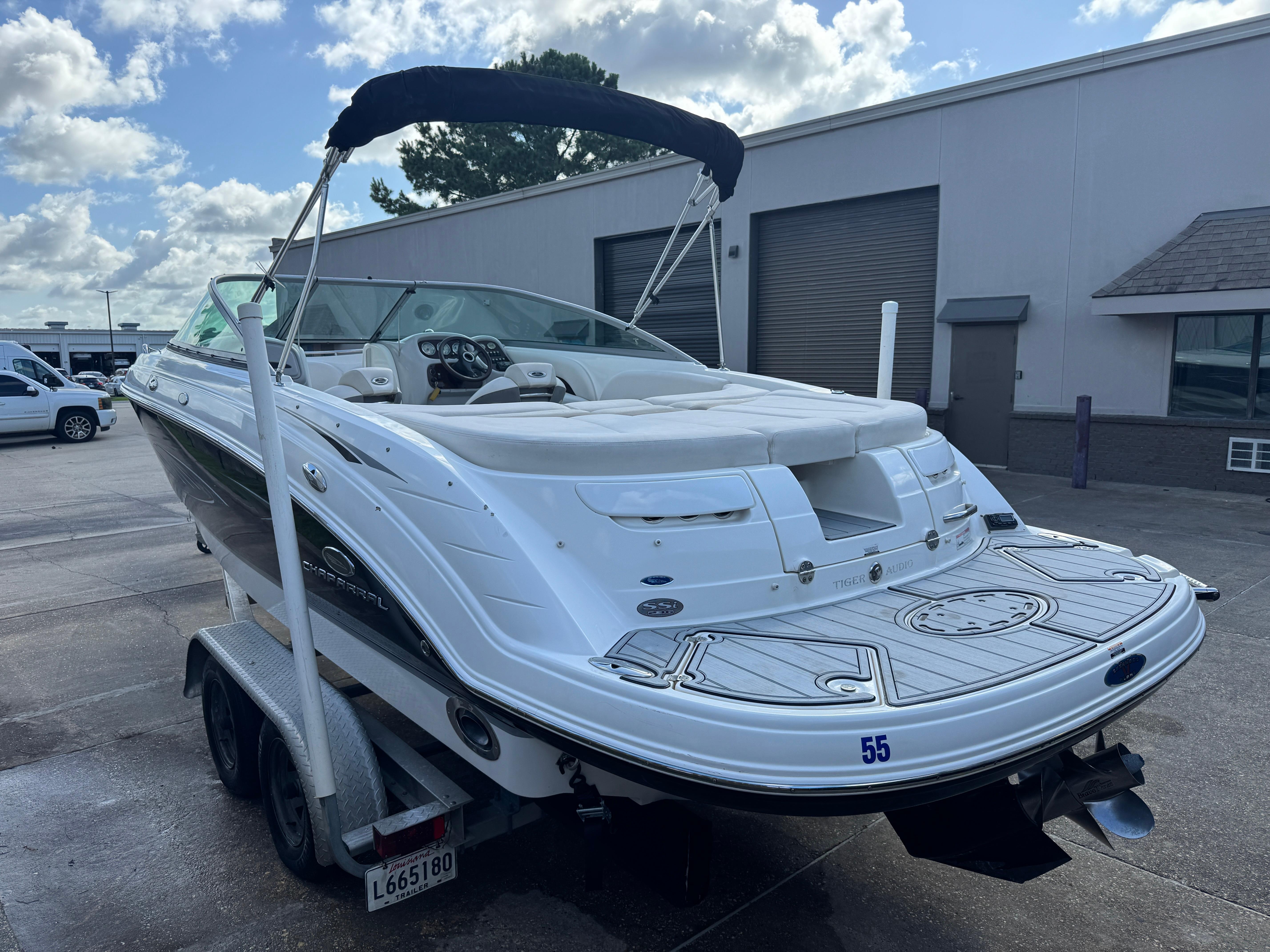 2006 Chaparral 236 SSi boat on trailer, parked outdoors under a cloudy sky.