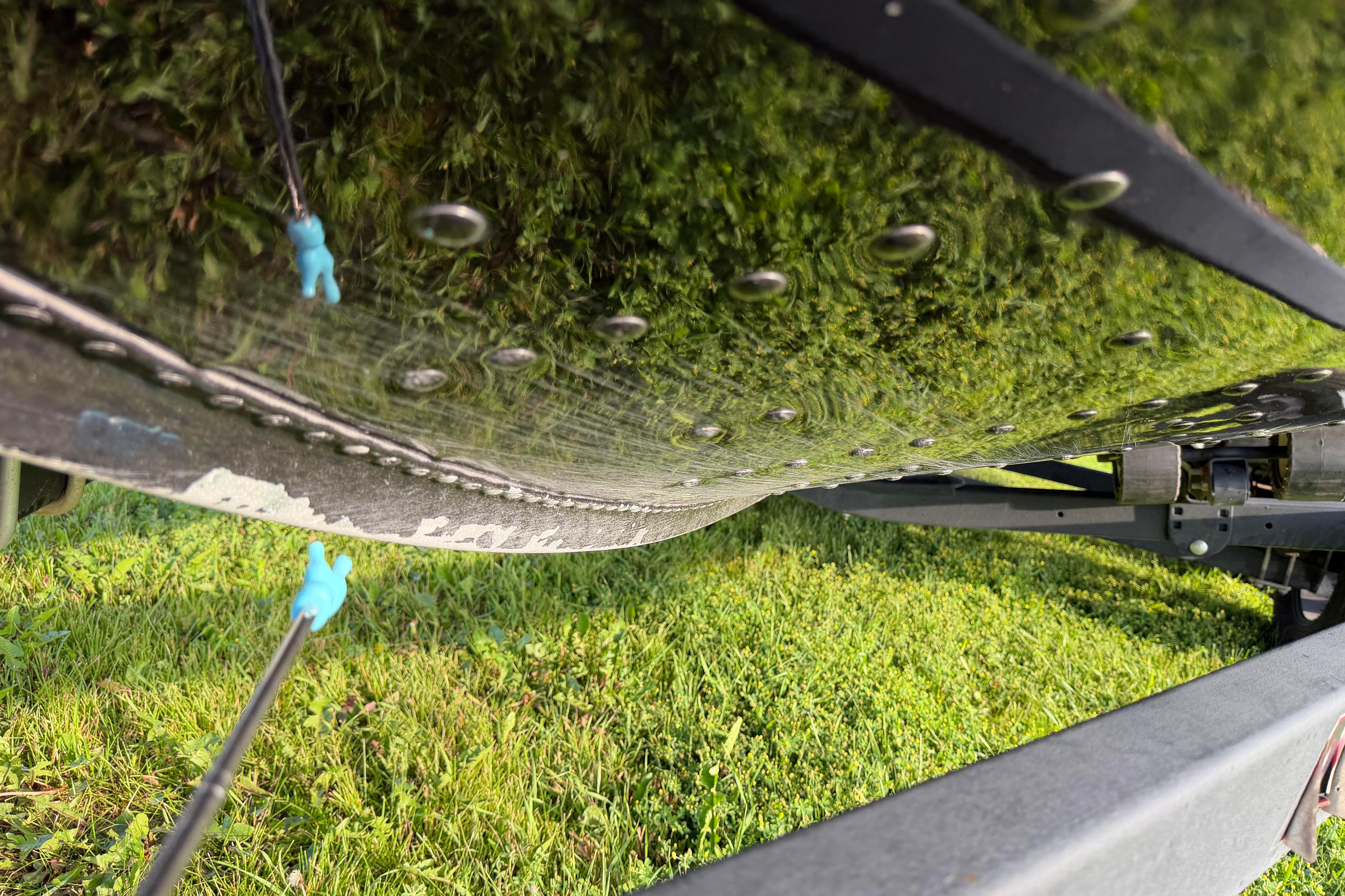 2019 Alumacraft Trophy 205 boat hull with moss, viewed from below on grassy surface.