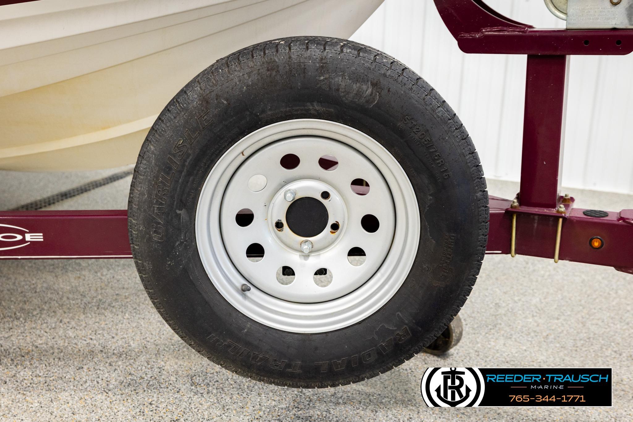 Trailer wheel of a 2016 Tahoe 450 TS boat on a maroon frame.