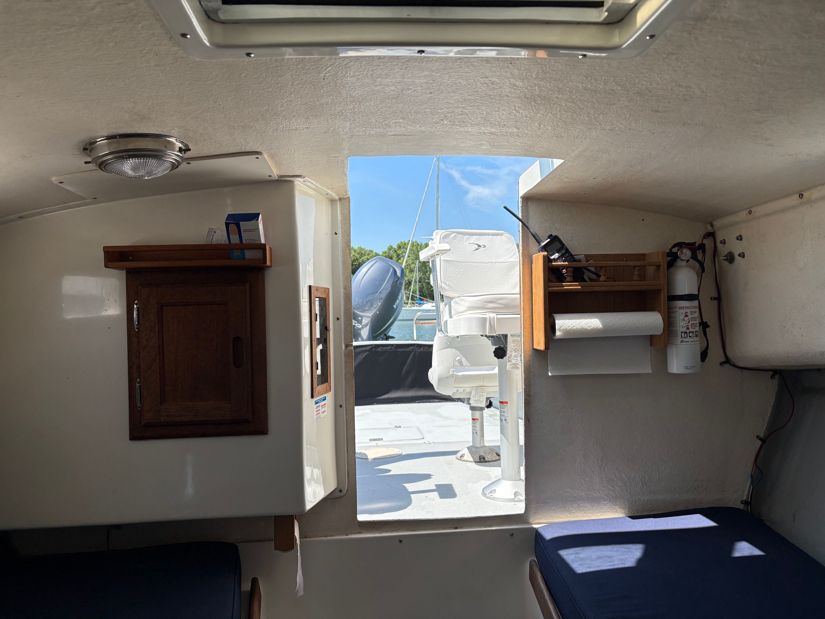Interior of a 1990 Portsmouth 22 with wooden cabinetry and a view of the deck.