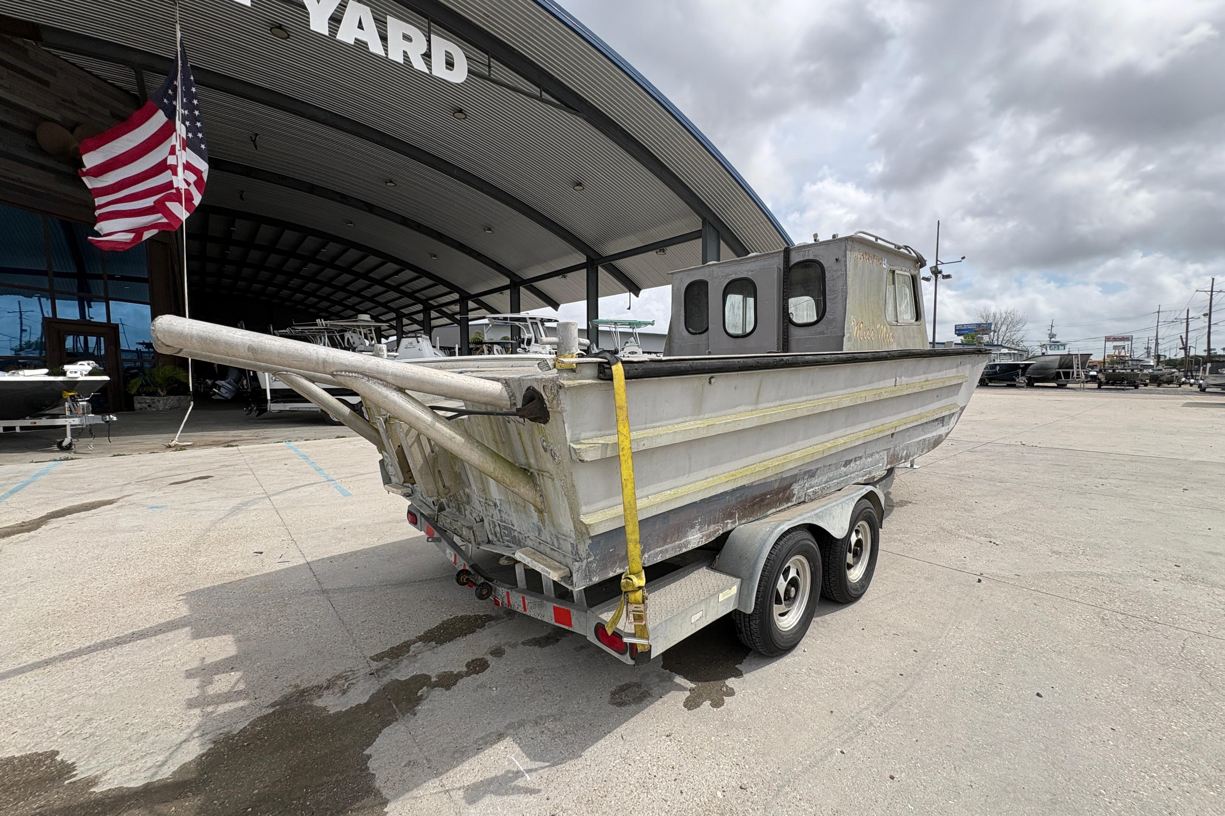 1972 Custom 23' work/push boat on trailer outside boatyard.