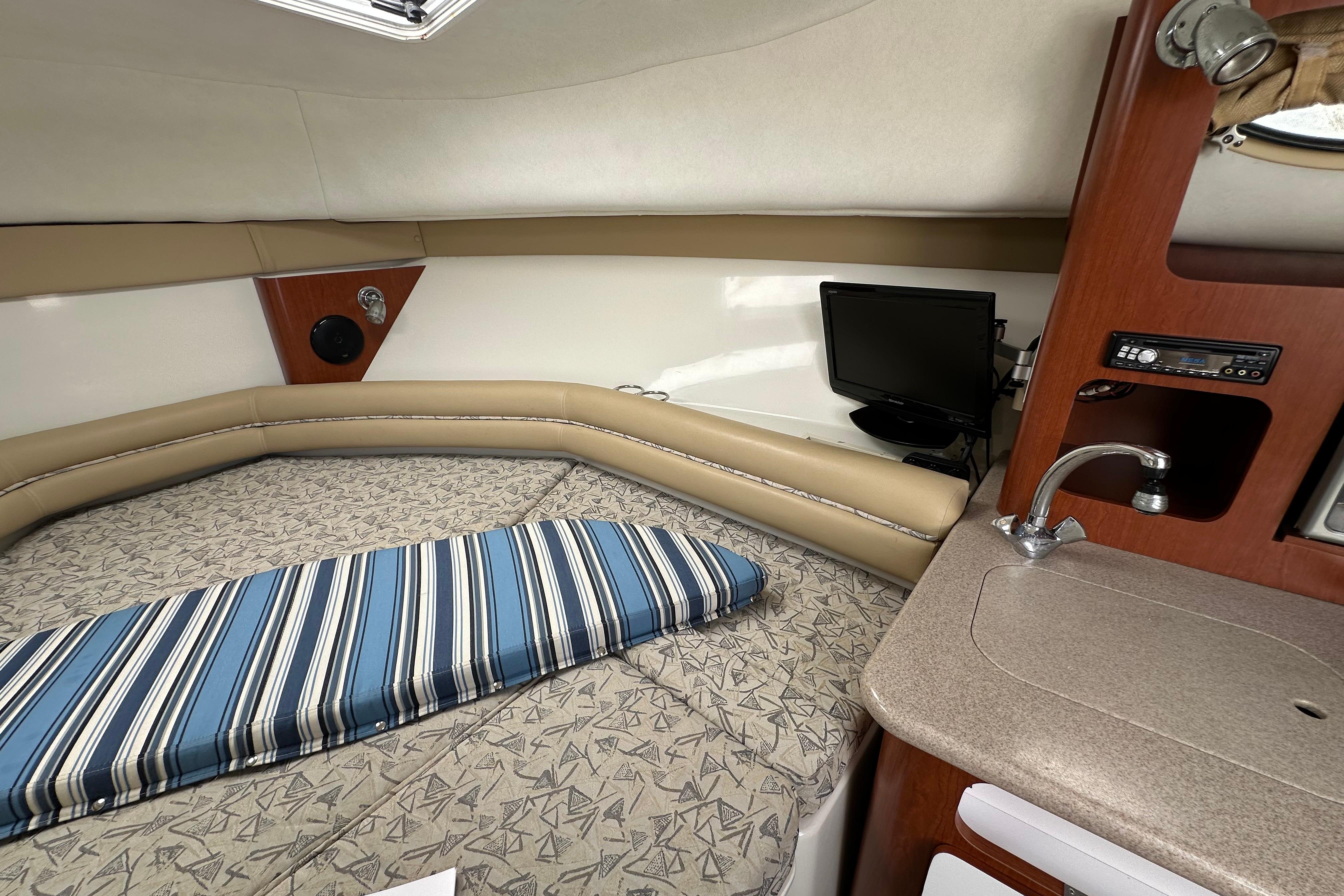 2006 Pro-Line 32 Express cabin interior with bed, TV, and compact kitchenette.