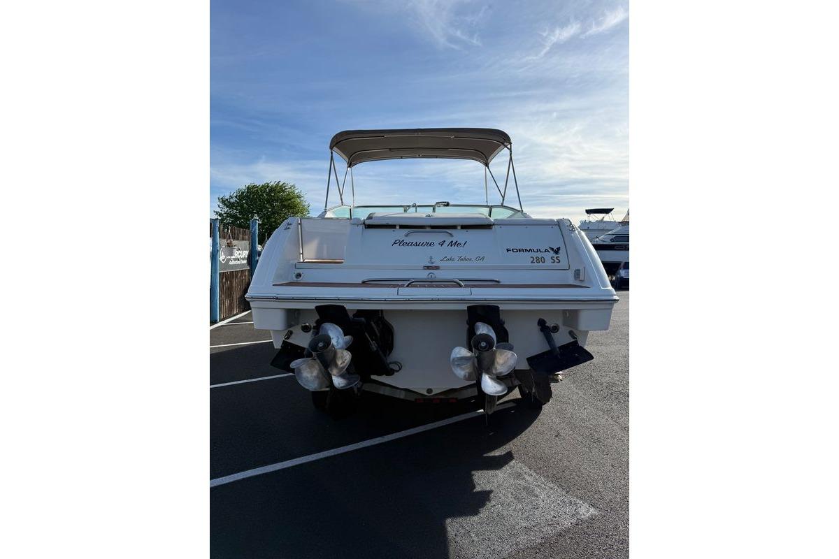 1999 Formula 280 Sun Sport boat, rear view, parked on asphalt under clear sky.