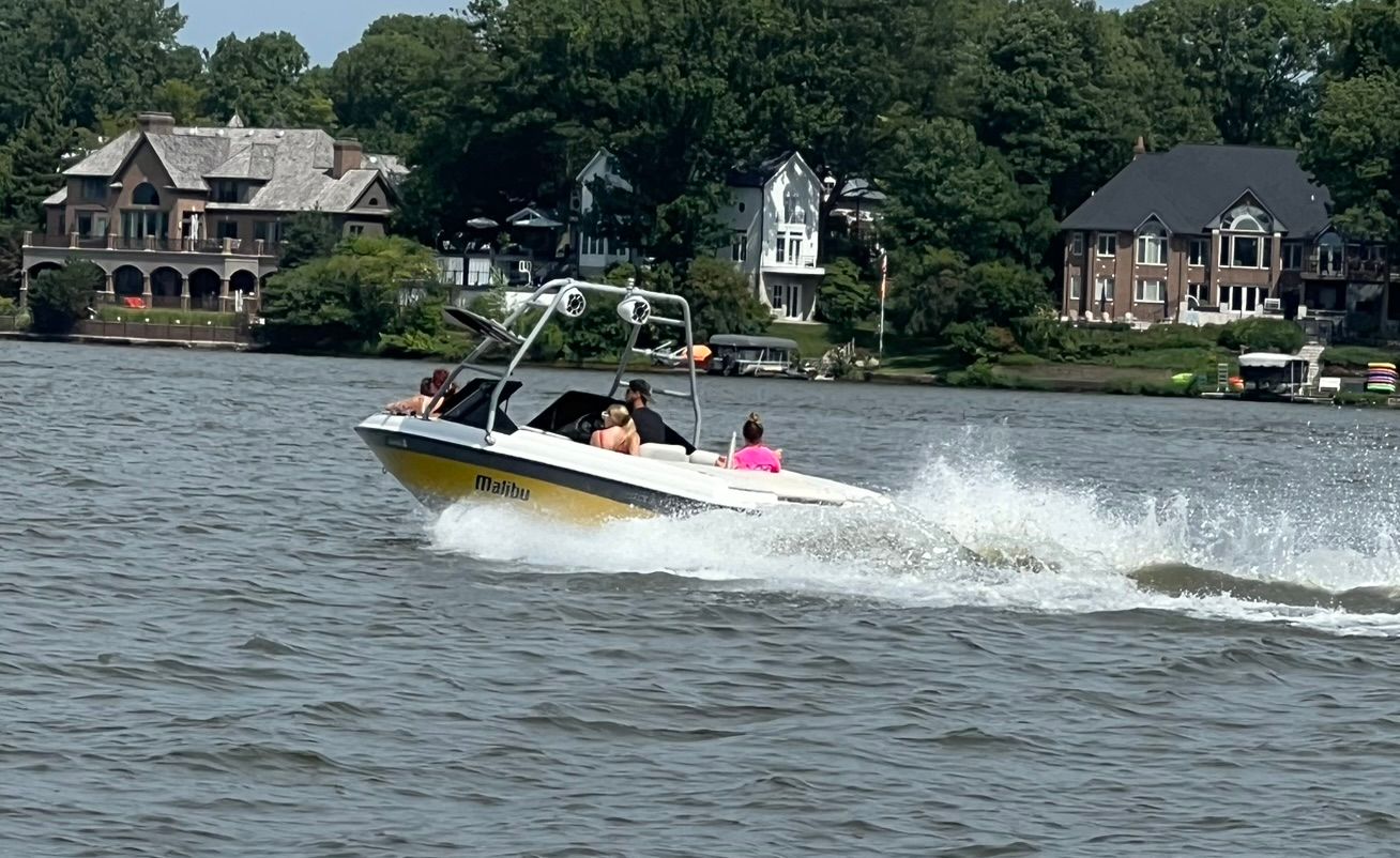 Malibu Wakesetter VLX 2000 on a lake with houses in background.